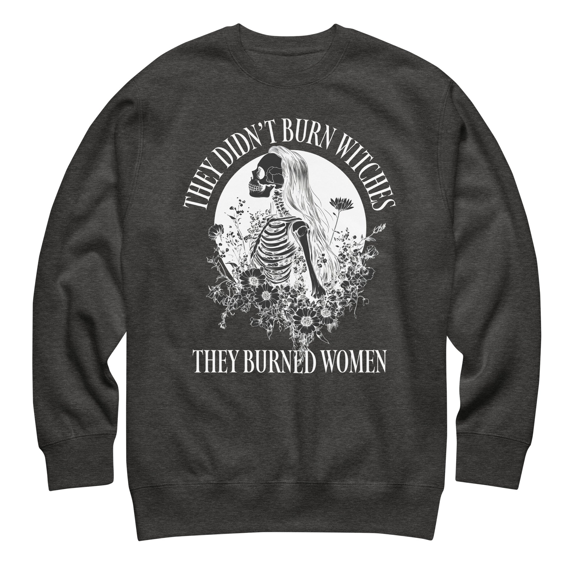 Charcoal heather unisex premium sweatshirt laid flat featuring gothic skeleton illustration with floral accents, centered circular layout, printed message “THEY DIDN’T BURN WITCHES THEY BURNED WOMEN.”