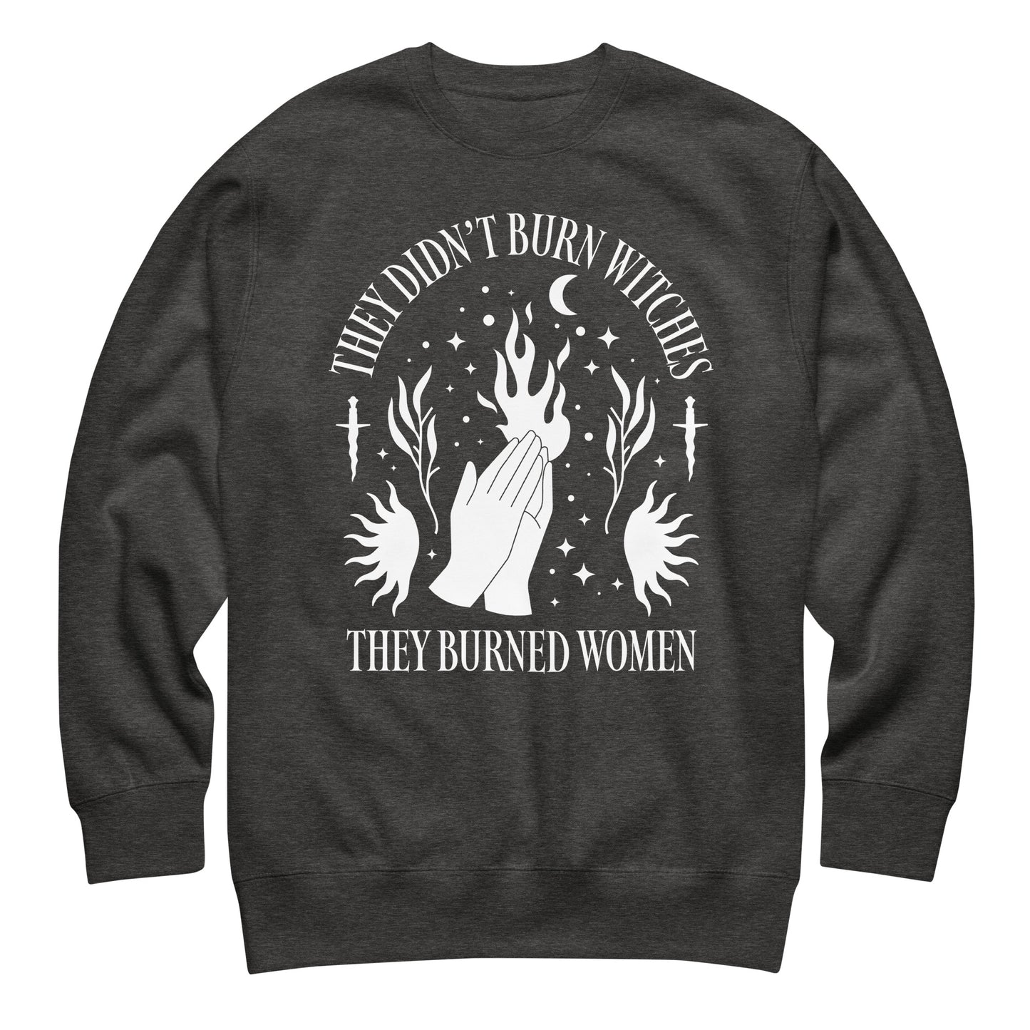 Charcoal heather unisex premium sweatshirt laid flat featuring white illustration of hands, flames, and stars, centered composition, printed message “THEY DIDN’T BURN WITCHES THEY BURNED WOMEN.”
