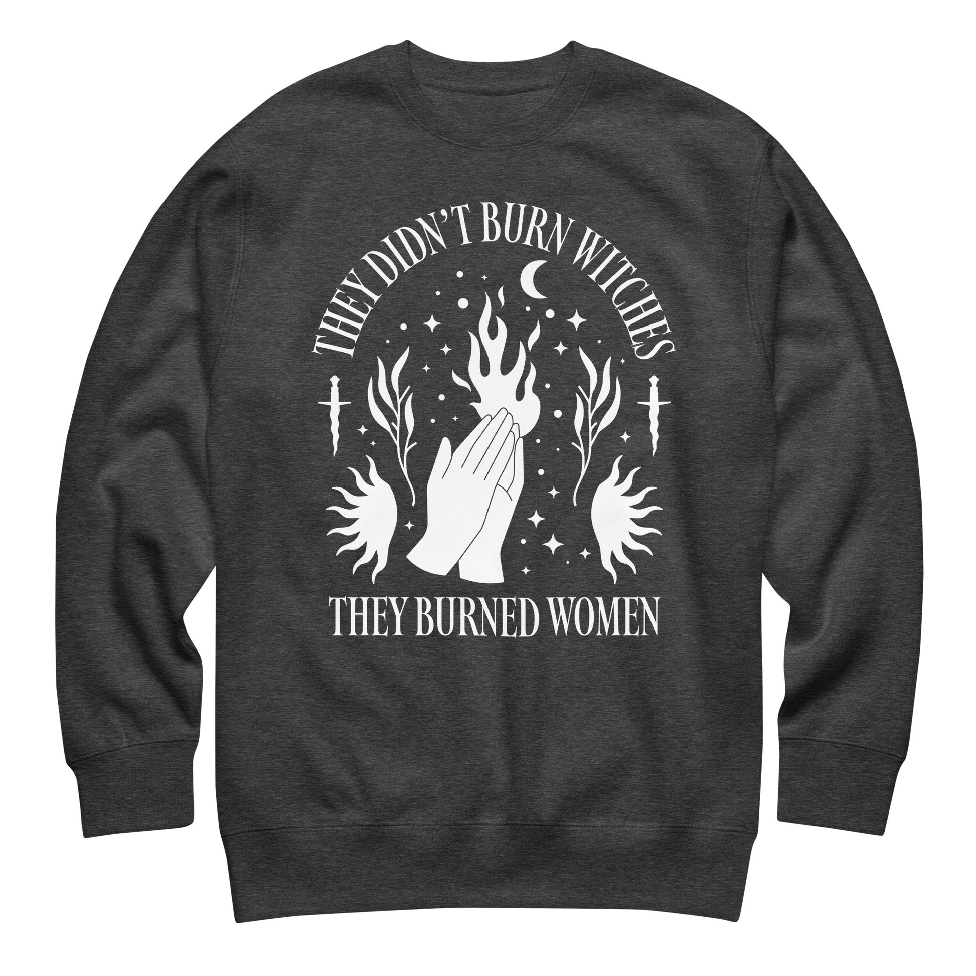 Charcoal heather unisex premium sweatshirt laid flat featuring white illustration of hands, flames, and stars, centered composition, printed message “THEY DIDN’T BURN WITCHES THEY BURNED WOMEN.”