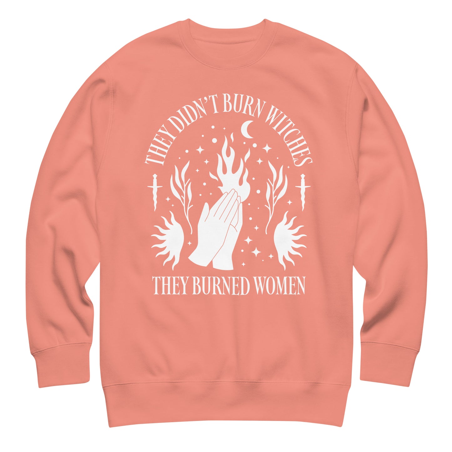 Peach unisex premium sweatshirt featuring bold occult-style illustration with raised hands and flame motifs, centered layout, printed message “THEY DIDN’T BURN WITCHES THEY BURNED WOMEN,” by Blue Wave USA.