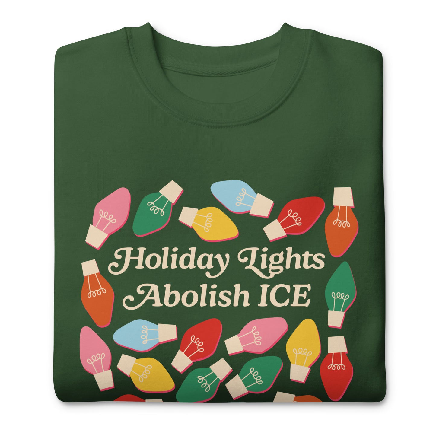 A green unisex sweatshirt decorated with cheerful holiday bulbs around the message “Holiday Lights Abolish ICE,” presented folded to showcase its bright festive activism style from Blue Wave USA.