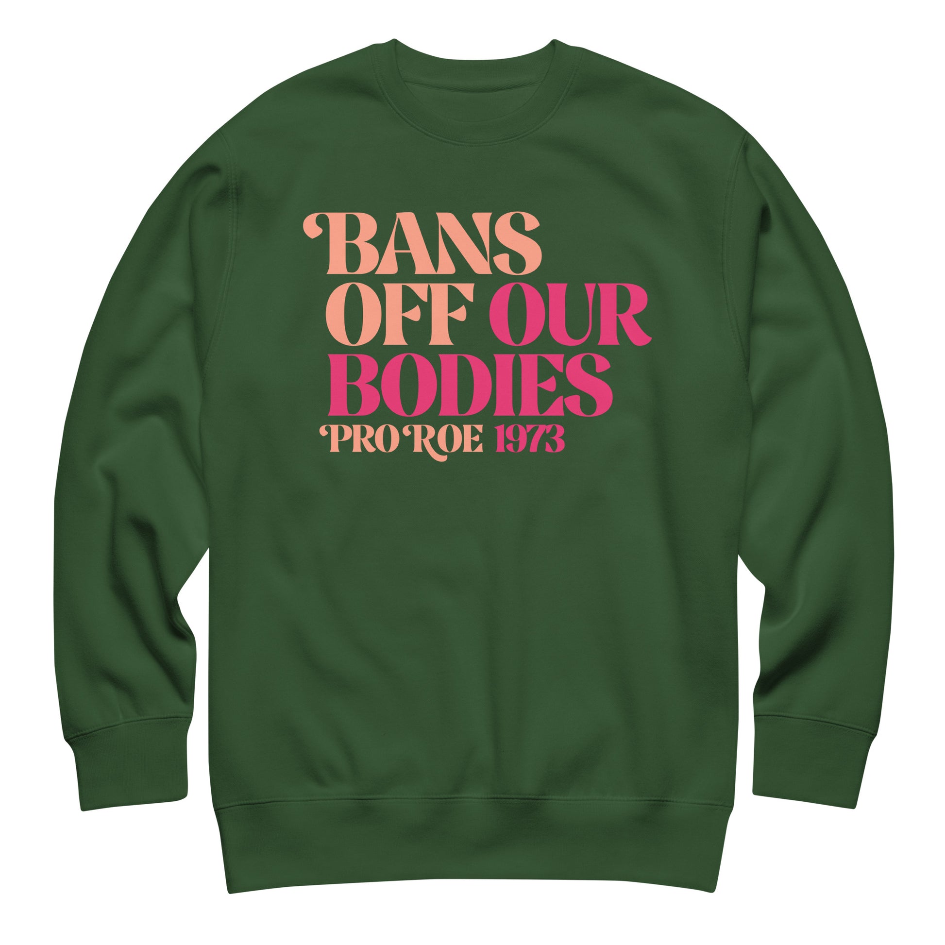 Forest green unisex premium sweatshirt laid flat featuring retro serif lettering in warm pink gradient, centered layout, printed message “BANS OFF OUR BODIES PRO ROE 1973.”