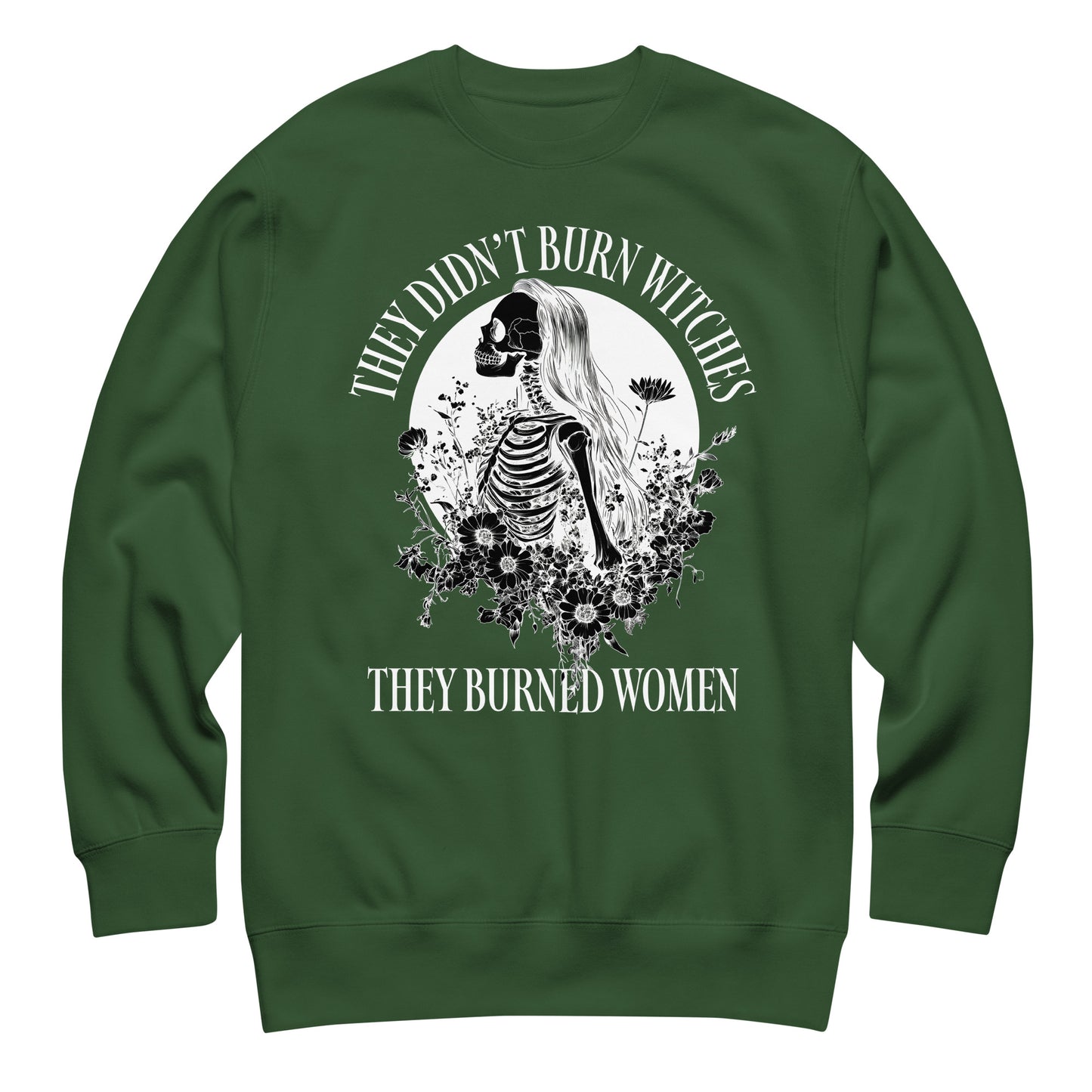 Forest green unisex premium sweatshirt featuring detailed gothic skeleton illustration with botanical elements, balanced centered layout, printed message “THEY DIDN’T BURN WITCHES THEY BURNED WOMEN.”