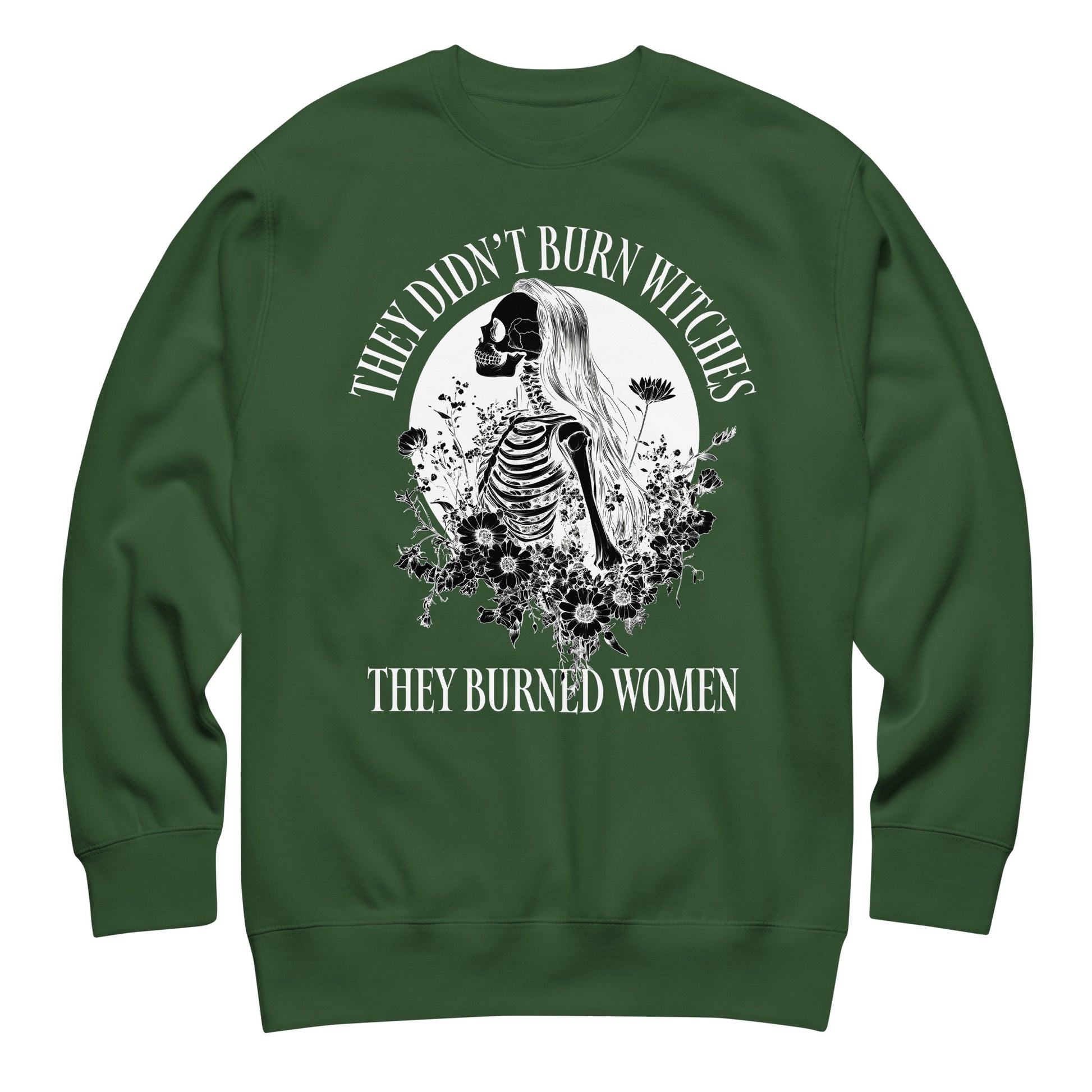 Forest green unisex premium sweatshirt featuring detailed gothic skeleton illustration with botanical elements, balanced centered layout, printed message “THEY DIDN’T BURN WITCHES THEY BURNED WOMEN.”