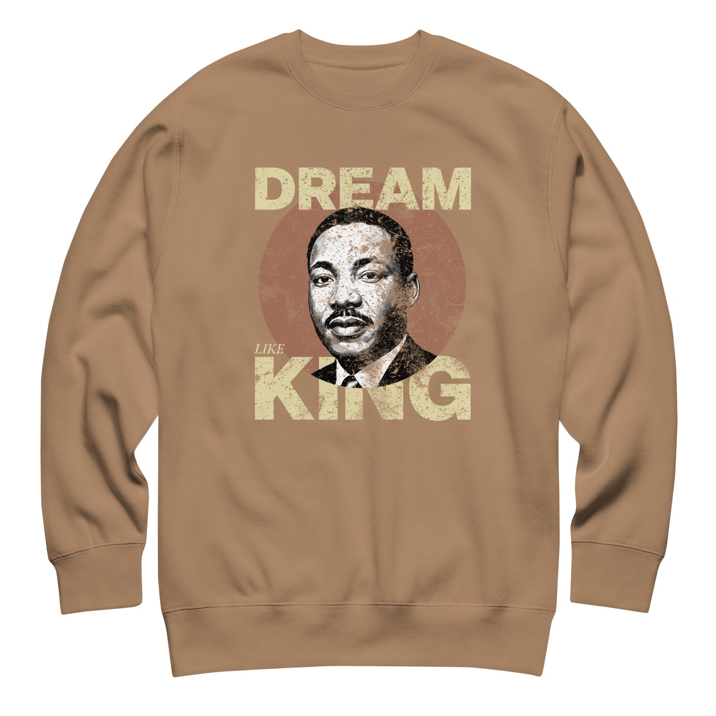 Tan unisex premium sweatshirt featuring distressed “DREAM LIKE KING” text with MLK’s portrait inside a weathered circle. Vintage activist look.