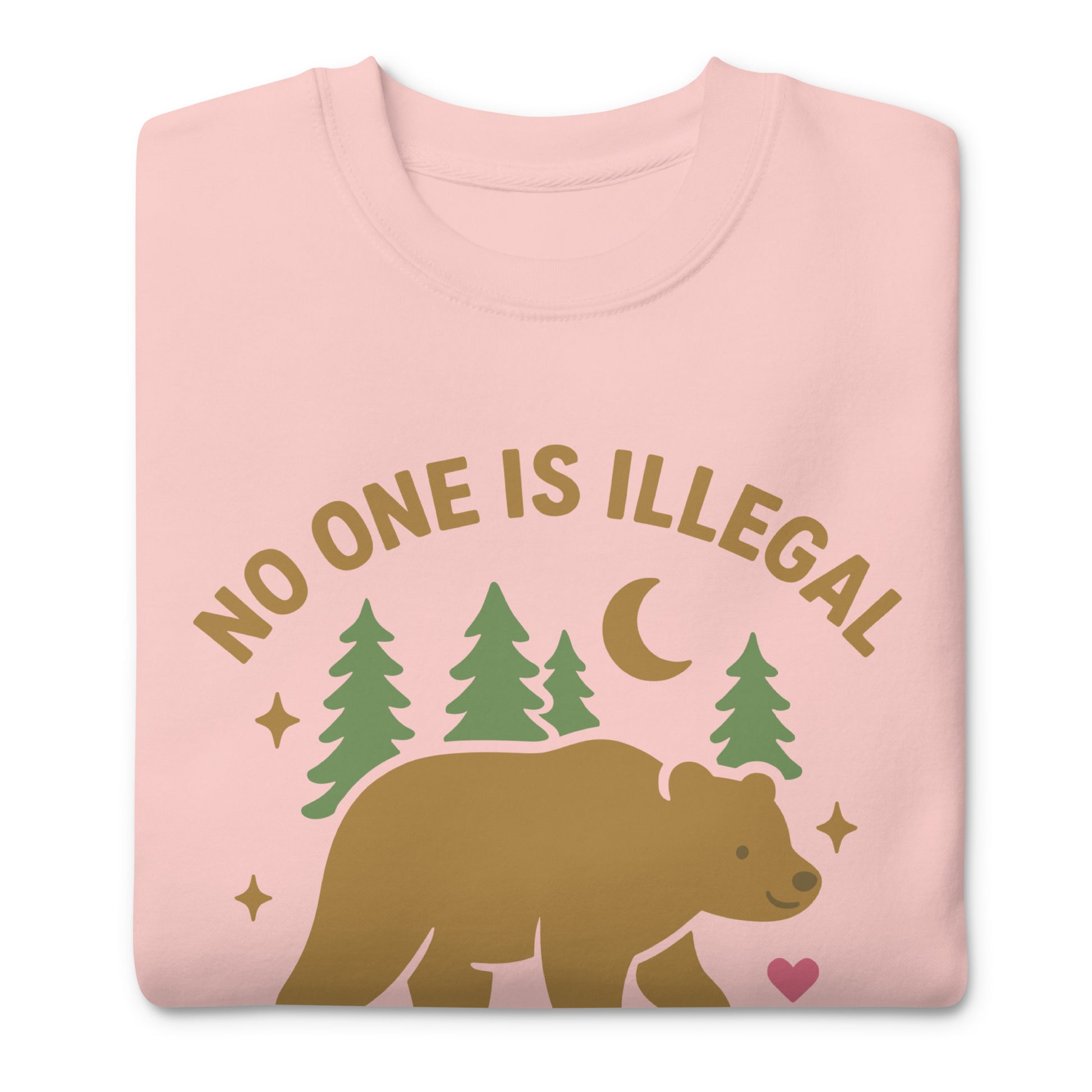 Pink unisex premium sweatshirt featuring the tan bear, trees, moon, and stars surrounding the message “NO ONE IS ILLEGAL ON STOLEN LAND,” printed in gentle, nature-inspired colors.