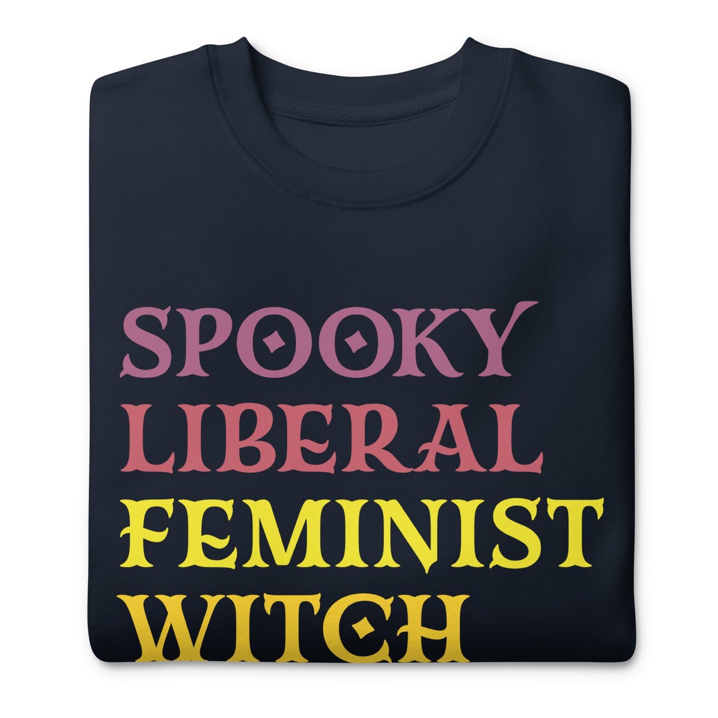 Folded navy unisex premium sweatshirt featuring stacked block lettering in pink, yellow, and purple, centered typographic design, printed message “SPOOKY LIBERAL FEMINIST WITCH.”