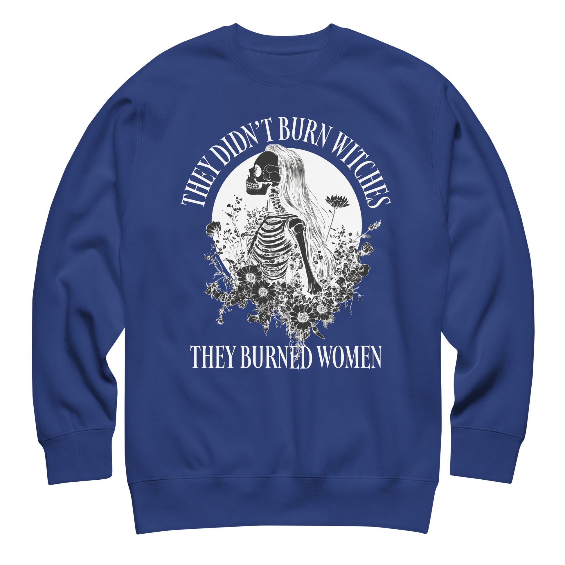 Royal blue unisex premium sweatshirt with intricate witch-inspired skeleton illustration in white ink, centered circular design, printed message “THEY DIDN’T BURN WITCHES THEY BURNED WOMEN.”