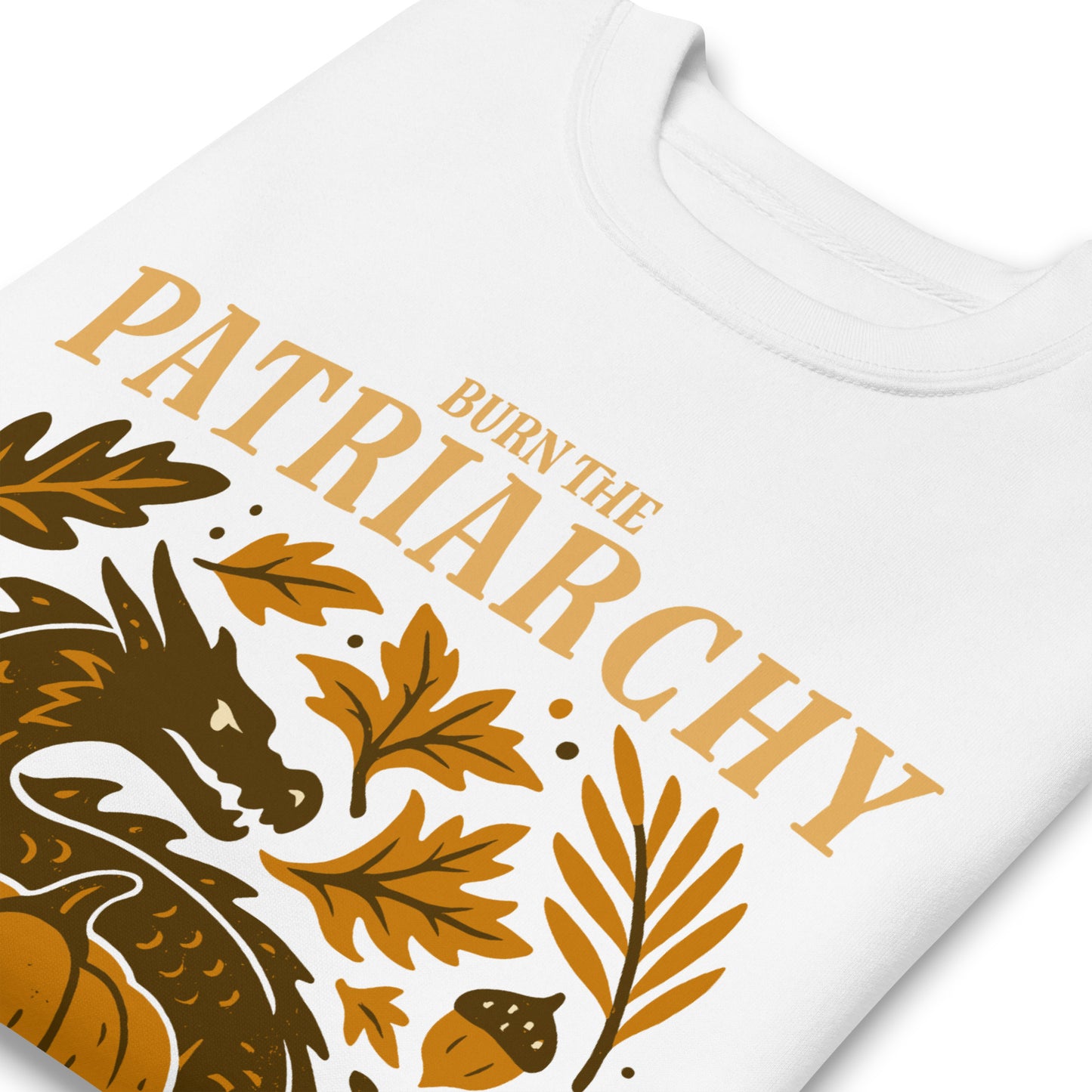 Close-up of “Burn the Patriarchy” golden dragon design on white sweatshirt, feminist Thanksgiving activism clothing detail shot.