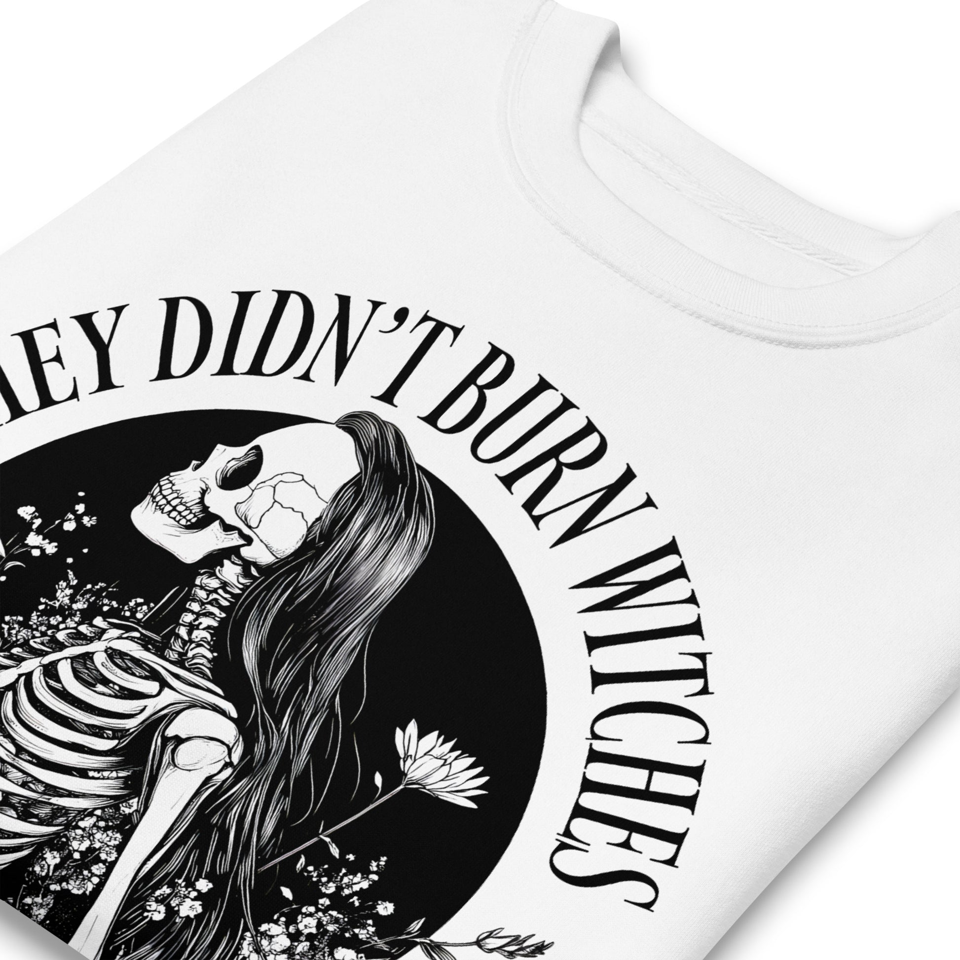 Close-up of white unisex premium sweatshirt showing detailed witch and skeleton illustration, fine linework and textured print, printed message “THEY DIDN’T BURN WITCHES THEY BURNED WOMEN.”