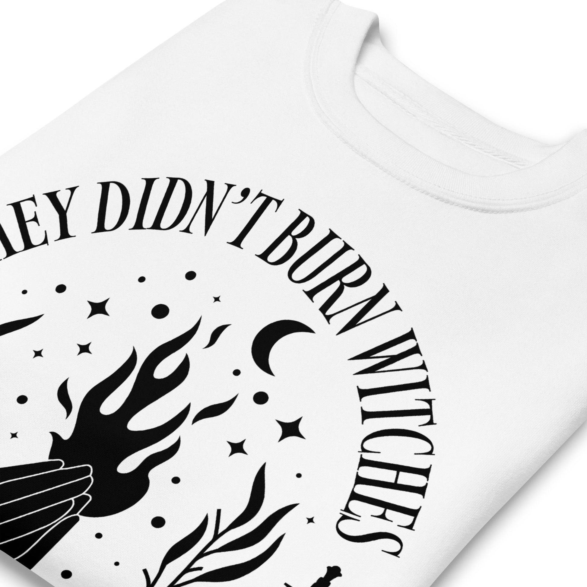 Close-up of white unisex premium sweatshirt showing detailed flame and celestial motifs, crisp black print texture, printed message “THEY DIDN’T BURN WITCHES THEY BURNED WOMEN.”