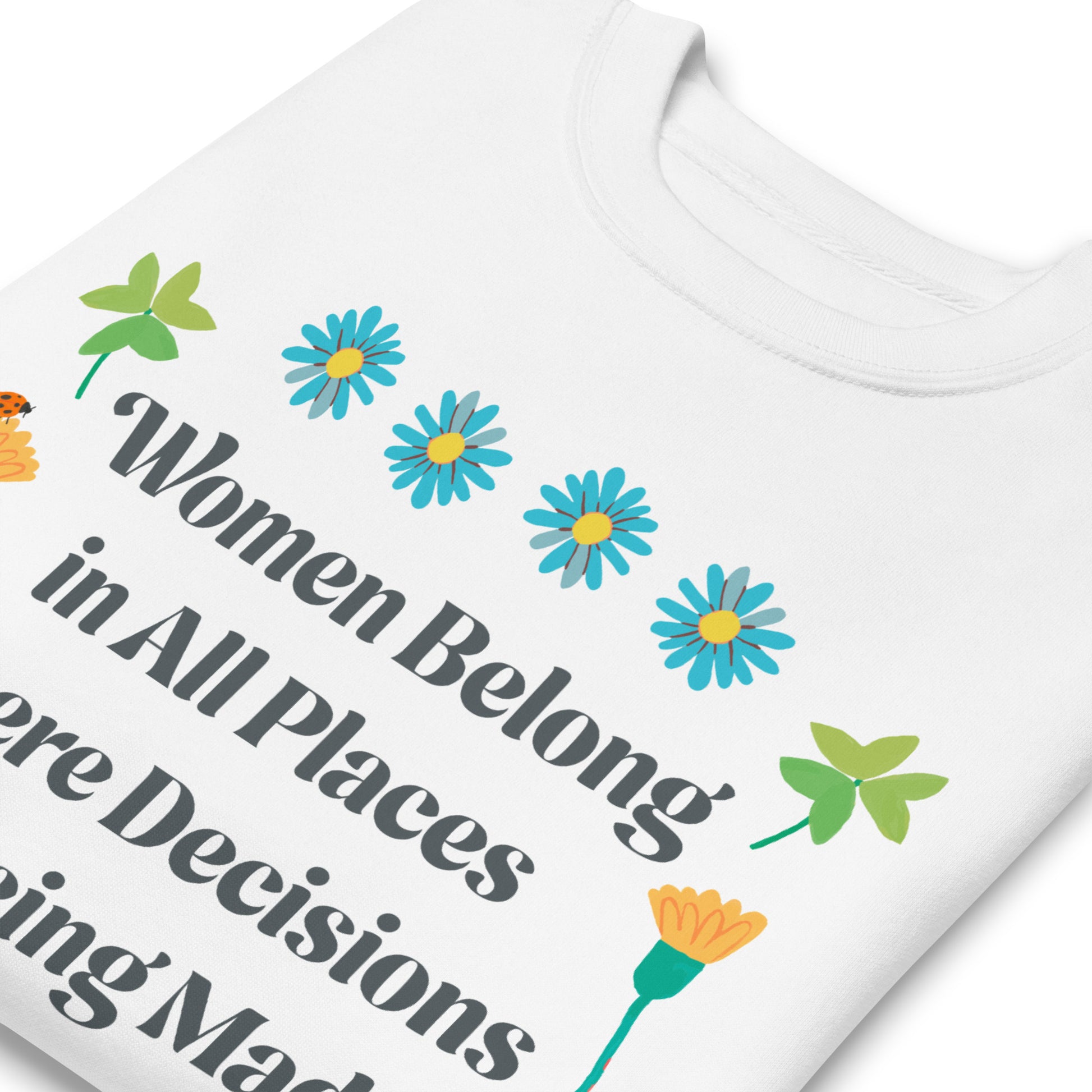 Close-up of white sweatshirt featuring floral Ruth Bader Ginsburg quote design reading “Women Belong in All Places Where Decisions Are Being Made.”