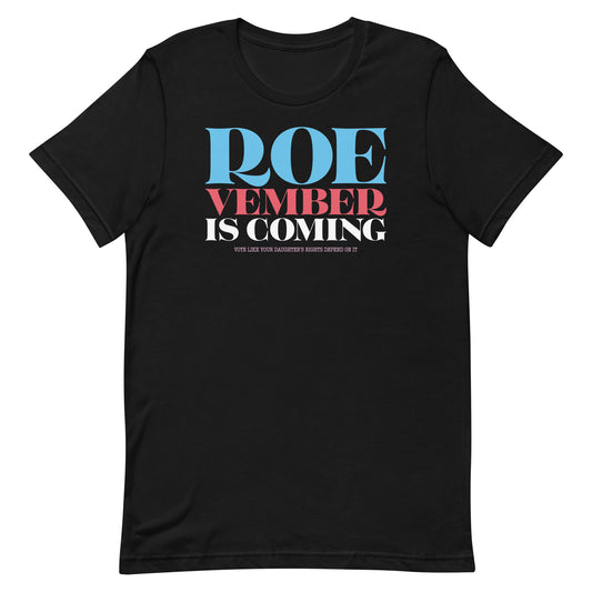 Black unisex t-shirt featuring bold stacked typography reading “Roevember Is Coming” in red, white, and blue, reproductive rights apparel from Blue Wave USA.