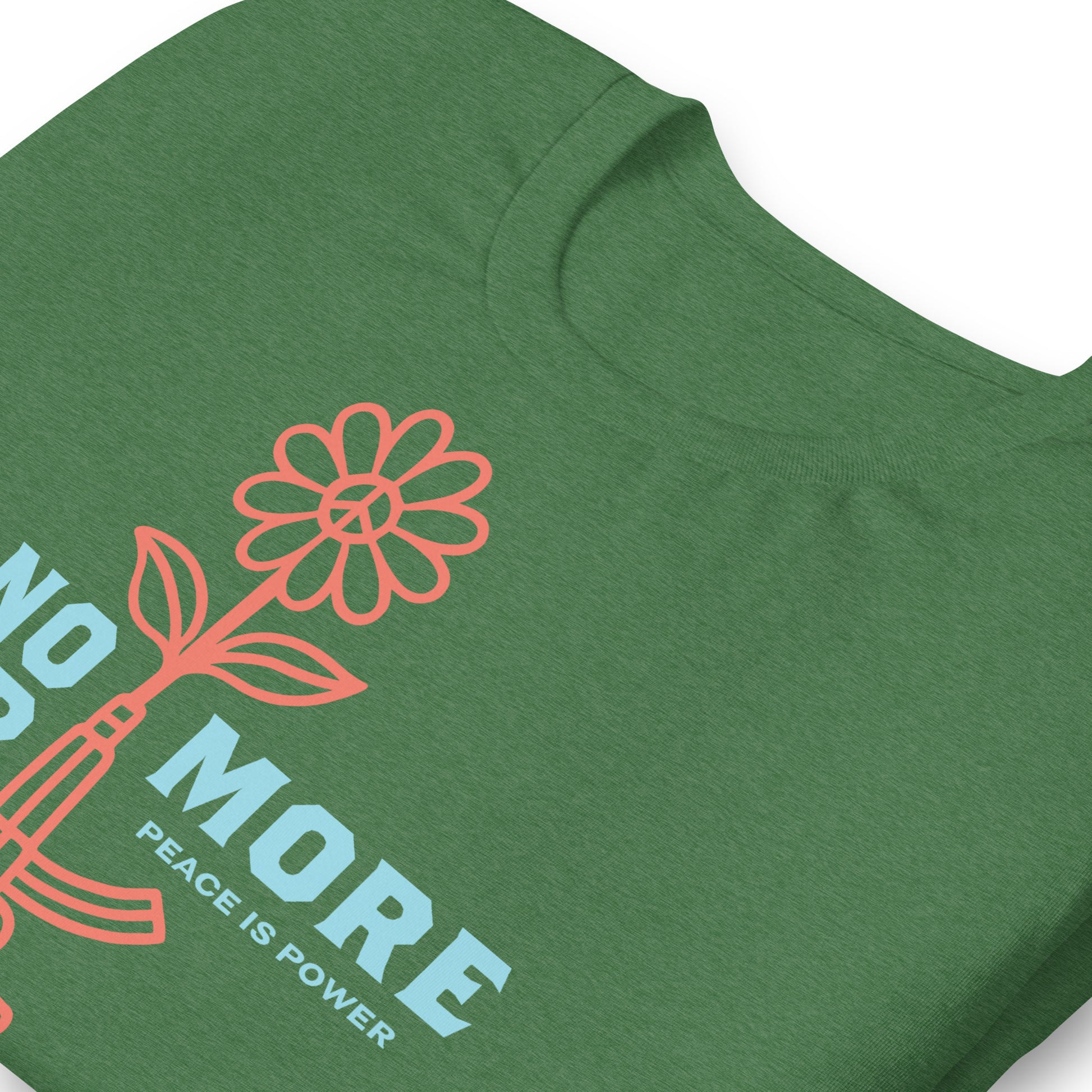 Close-up of graphic showing stylized rifle transforming into flower with “No More War” text, minimalist justice-focused design on heather grass green t-shirt fabric.