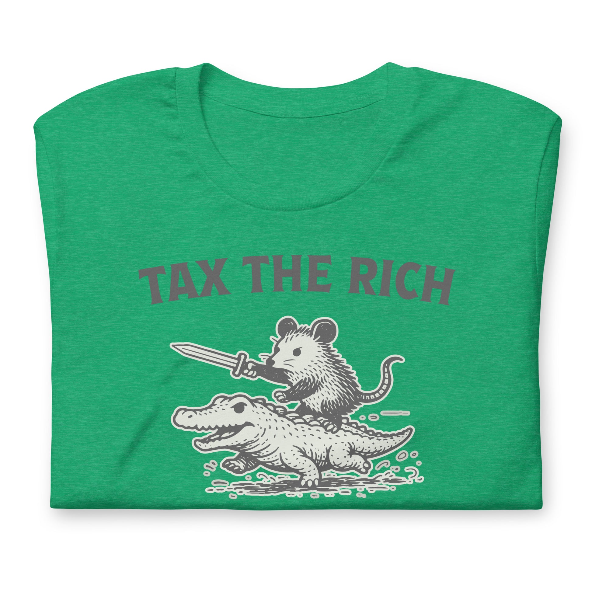Folded heather kelly green t-shirt displaying a monochrome opossum riding an alligator illustration paired with the “Tax the Rich” slogan inspired by economic justice and political satire.