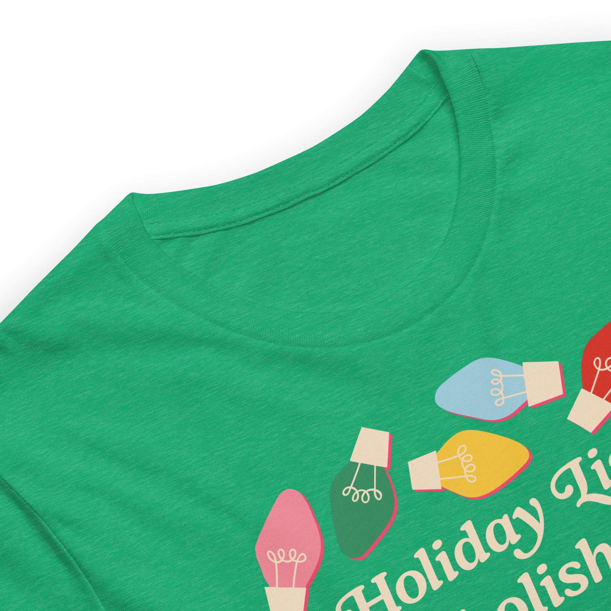 A close-up of a heather kelly unisex t-shirt showing vibrant holiday bulbs and part of the message “Holiday Lights Abolish ICE,” highlighting fabric texture and colorful holiday artwork.