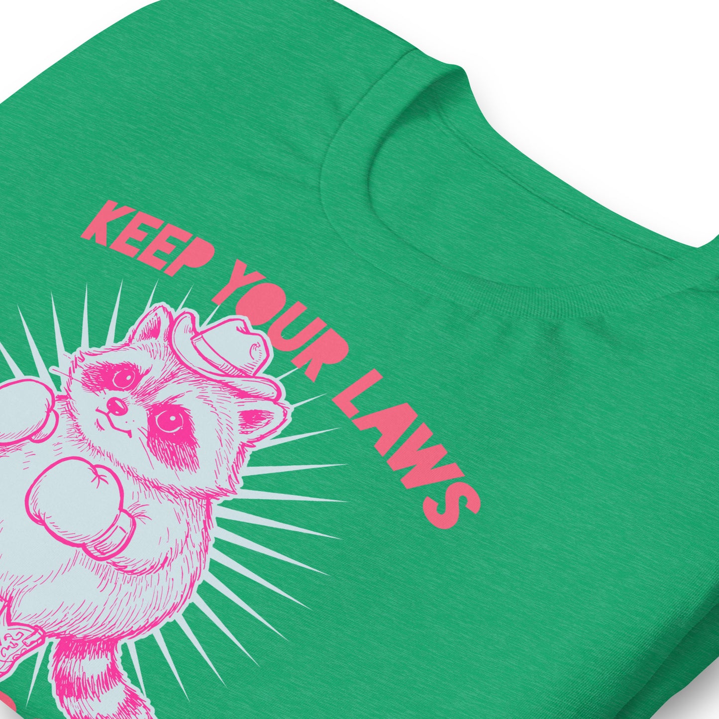 Close-up heather kelly green unisex T-shirt print showing pink raccoon cowboy artwork with “Off My Body” phrase in bold reproductive rights protest style.