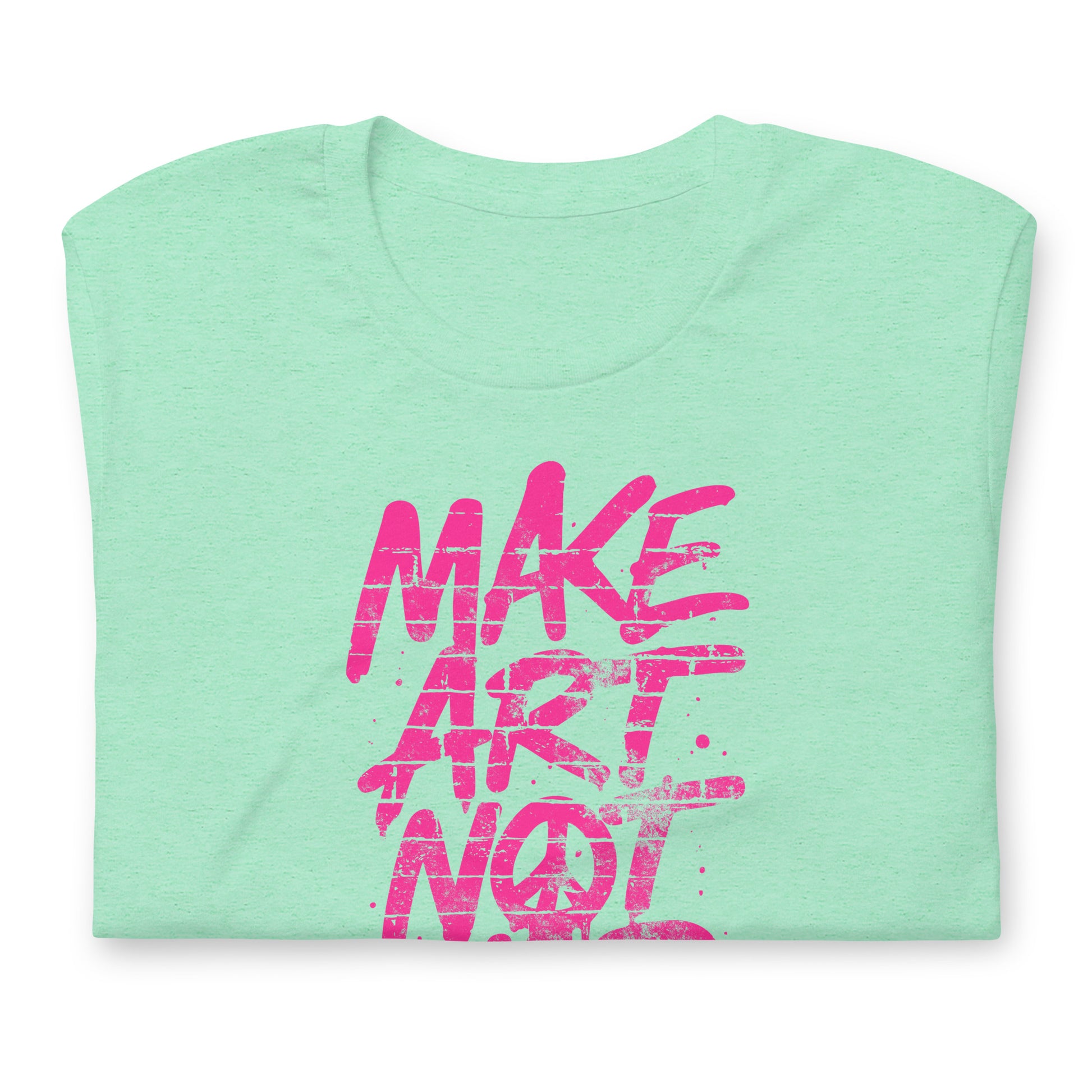 Folded heather mint green unisex t-shirt showing partial neon pink graffiti lettering from the phrase “MAKE ART NOT WAR,” emphasizing bold brushstroke texture and high-contrast street-art graphic style.