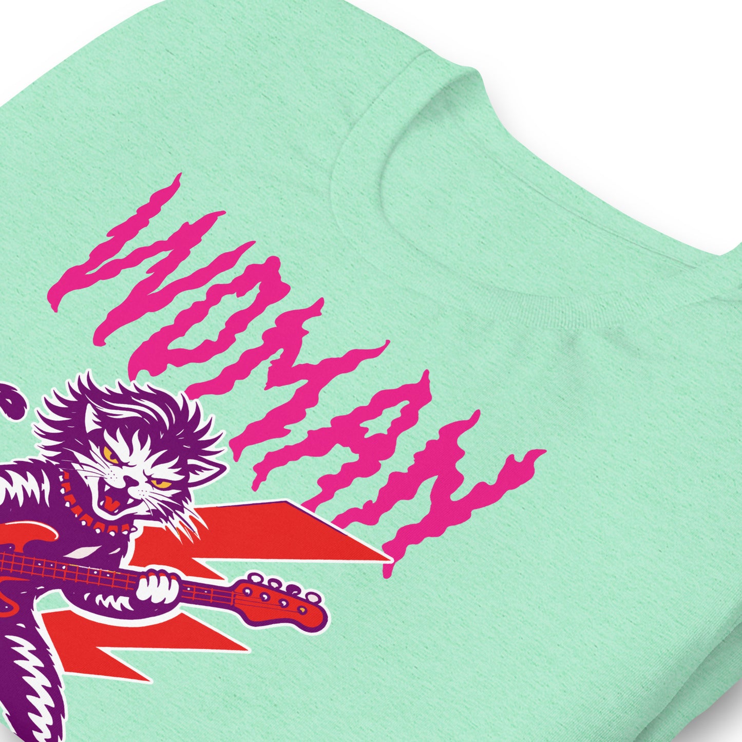 Close-up of a mint green unisex t-shirt highlighting distressed pink lettering reading “WOMAN OF A CERTAIN RAGE,” with partial view of the punk rock cat illustration.