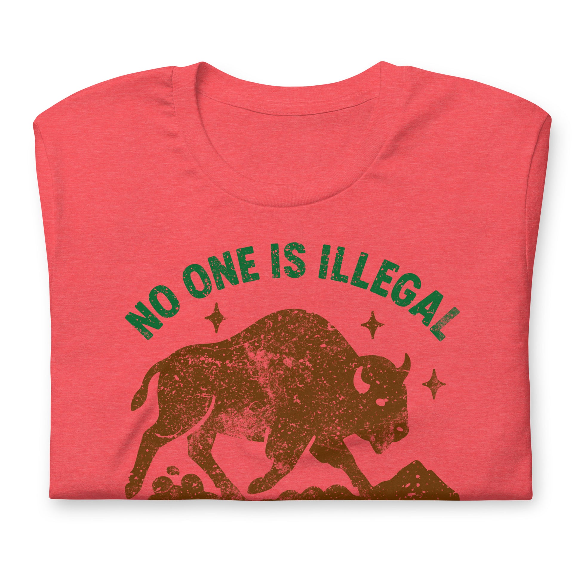 Red heather unisex t-shirt displaying a distressed buffalo graphic with stars and the text “NO ONE IS ILLEGAL ON STOLEN LAND,” shown in a warm, earthy activist style.