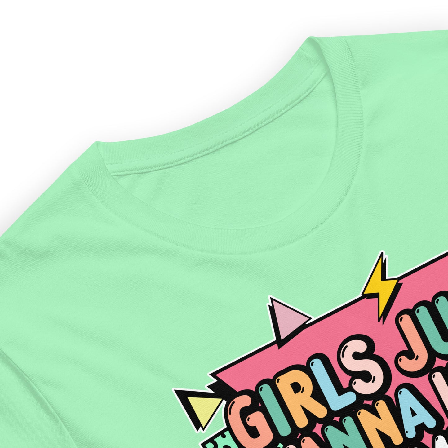 Folded mint green t-shirt showing bold feminist lettering “Girls Just Wanna Have Fundamental Human Rights” surrounded by pastel lightning bolts and geometric shapes.