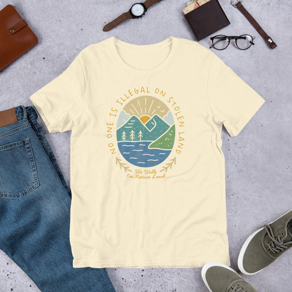 Flat Lay Image: Flat lay of decolonize-themed t-shirt with bold social justice message and illustrated landscape - Natural