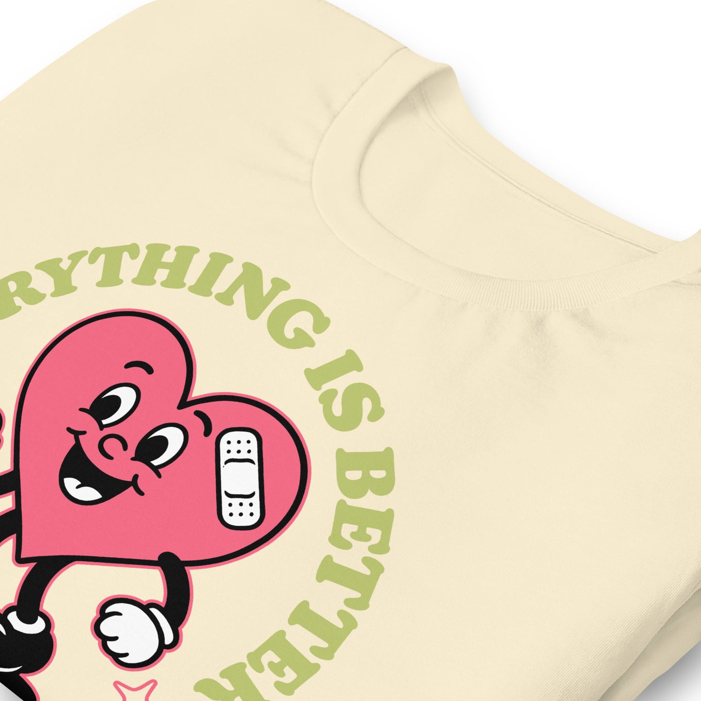 Close-up of cream “Everything Is Better with Healthcare” tee showing printed design details and heart character illustration.