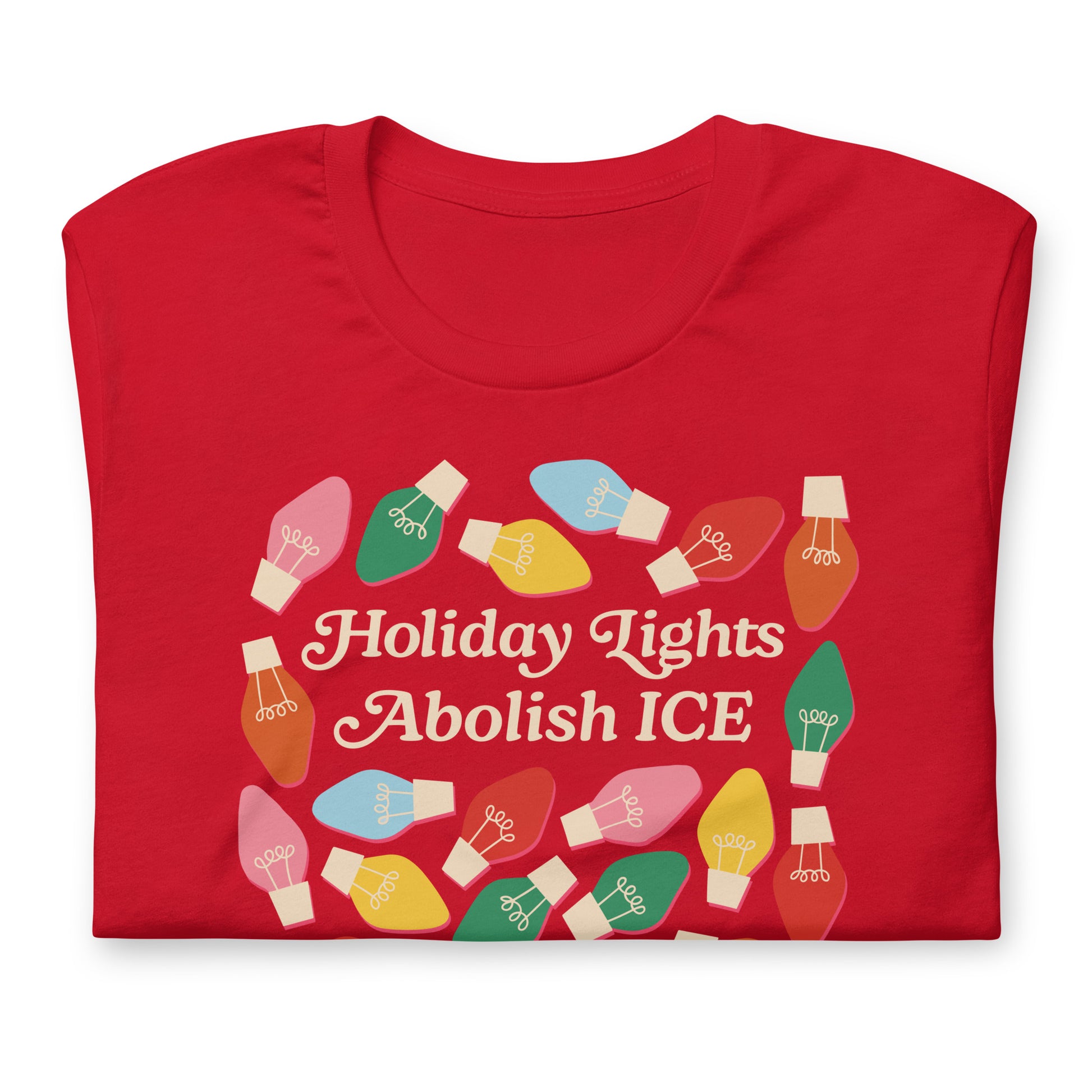 A red unisex t-shirt printed with multicolored holiday light bulbs circling the message “Holiday Lights Abolish ICE,” creating a cheerful activist Christmas style.