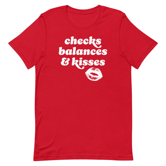 Red unisex t-shirt showcasing rounded vintage text and lips artwork with the phrase “checks balances & kisses,” a justice-focused Valentine design.