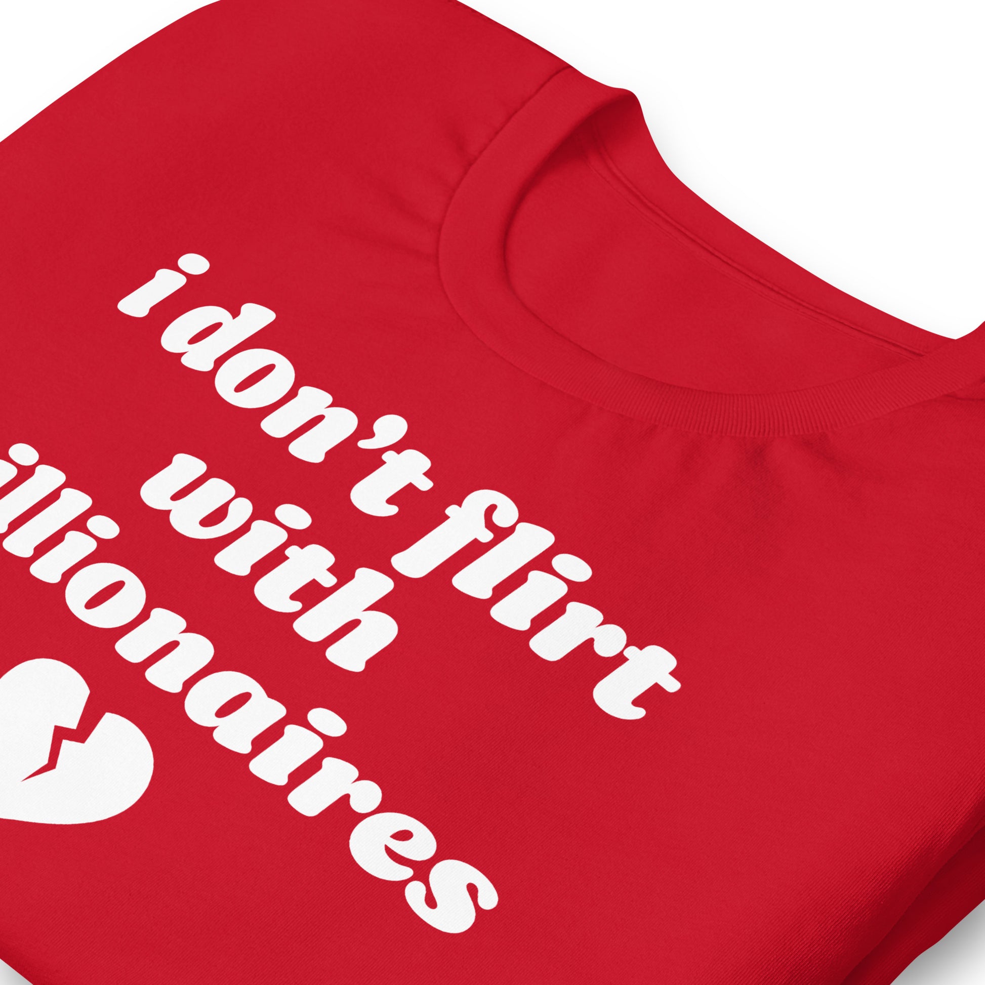Close-up of red unisex t-shirt collar and print showing the phrase “i don’t flirt with billionaires” with a small broken heart graphic.