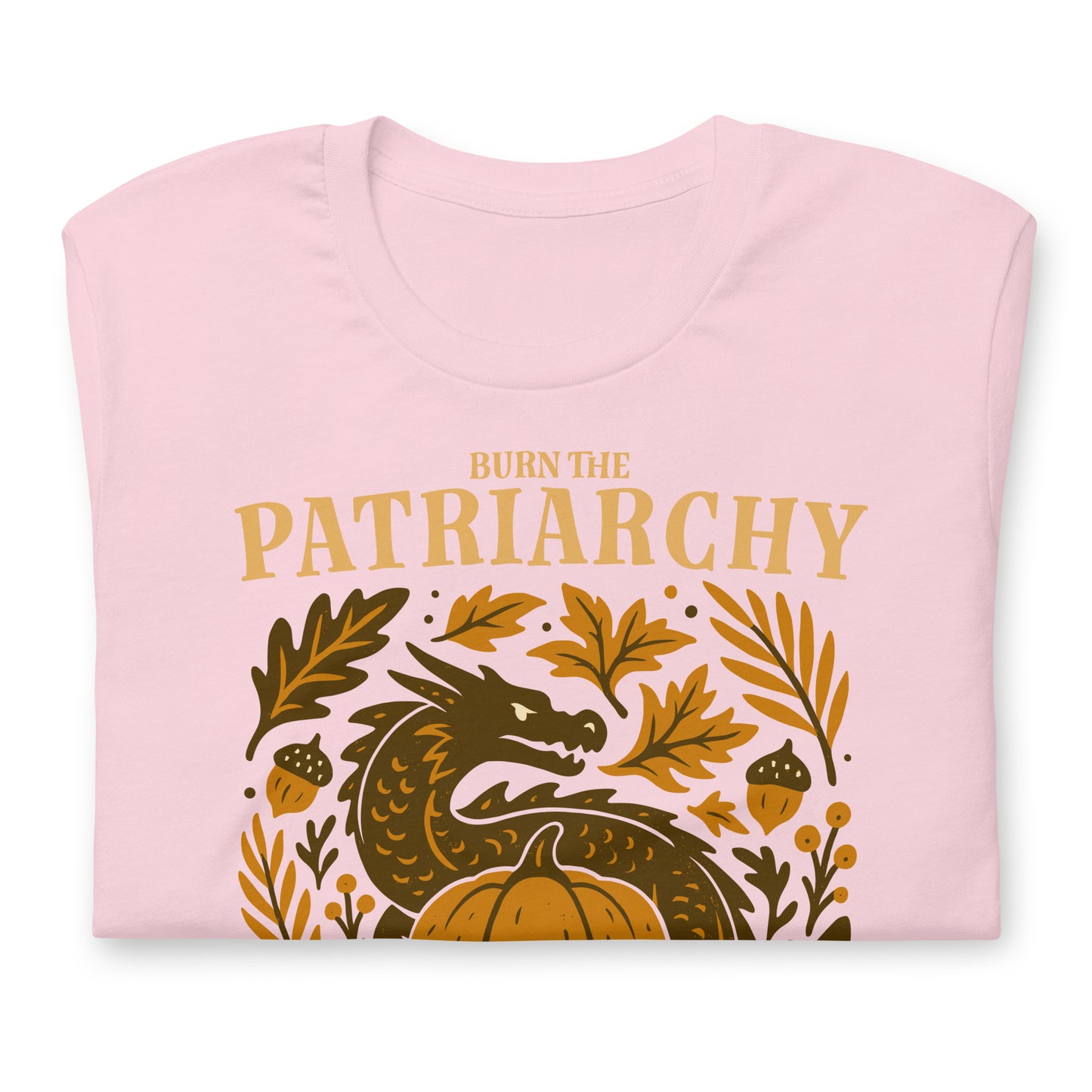 Folded light pink “Burn the Patriarchy” dragon and pumpkin feminist t-shirt with botanical leaves and acorns.