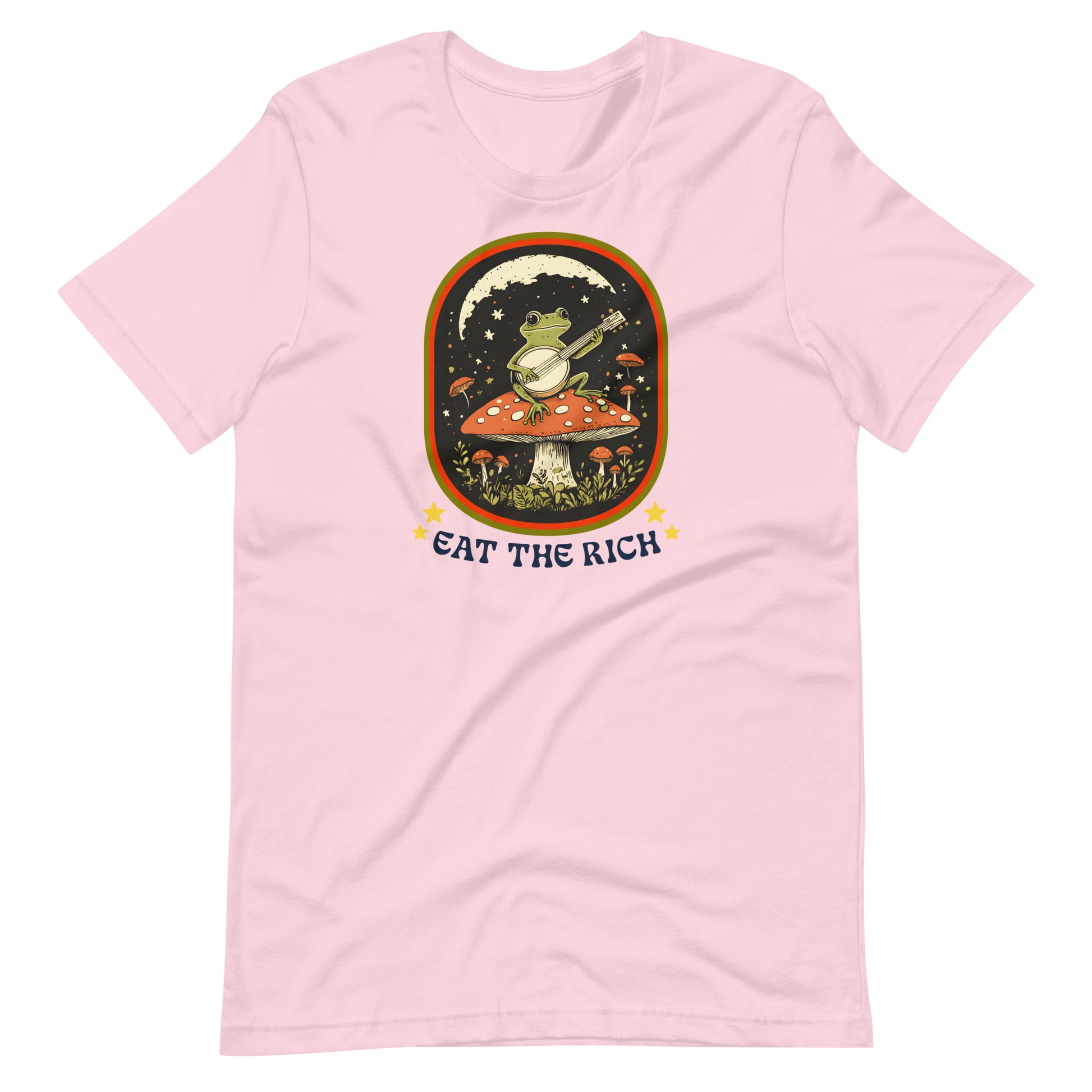 Soft pink unisex t-shirt showcasing a folk-art frog playing a banjo with vintage-inspired “Eat The Rich” anti-capitalist protest artwork.