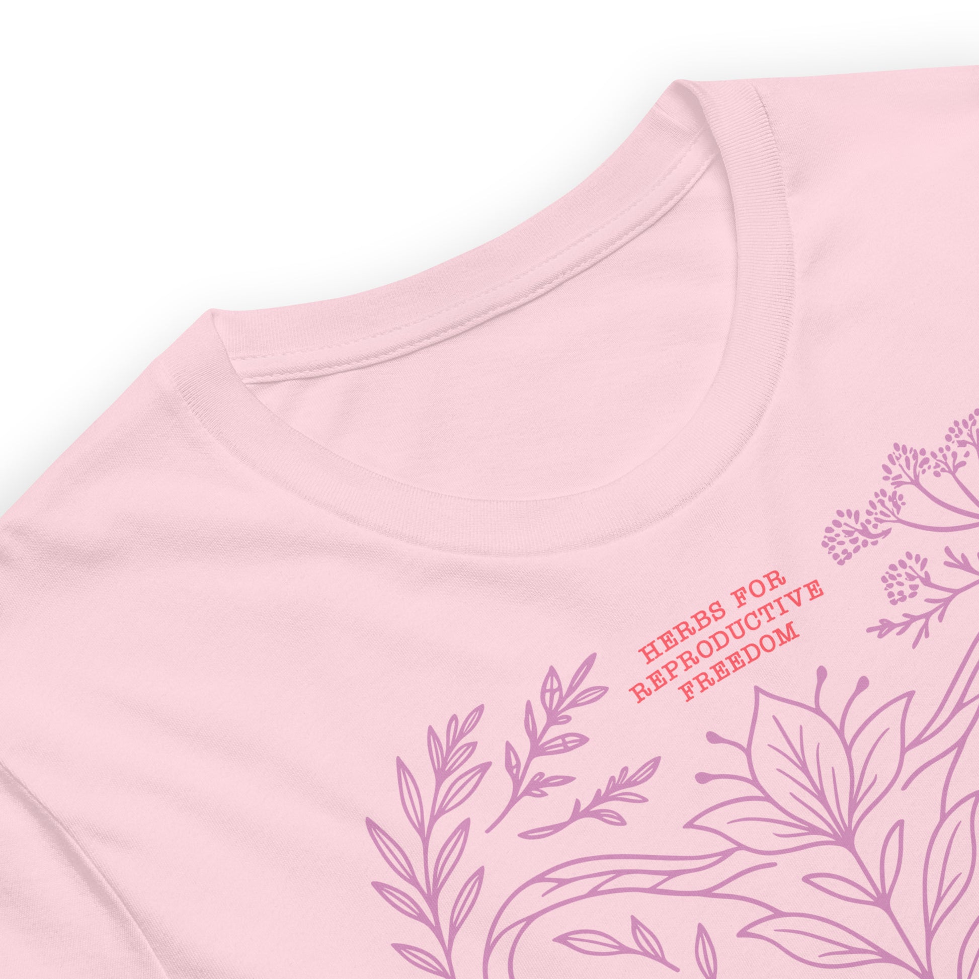 Close-up of the light pink “Herbs for Reproductive Freedom” t-shirt showing delicate lavender herbal linework and text detail near the neckline. Soft feminist botanical apparel by Blue Wave USA.