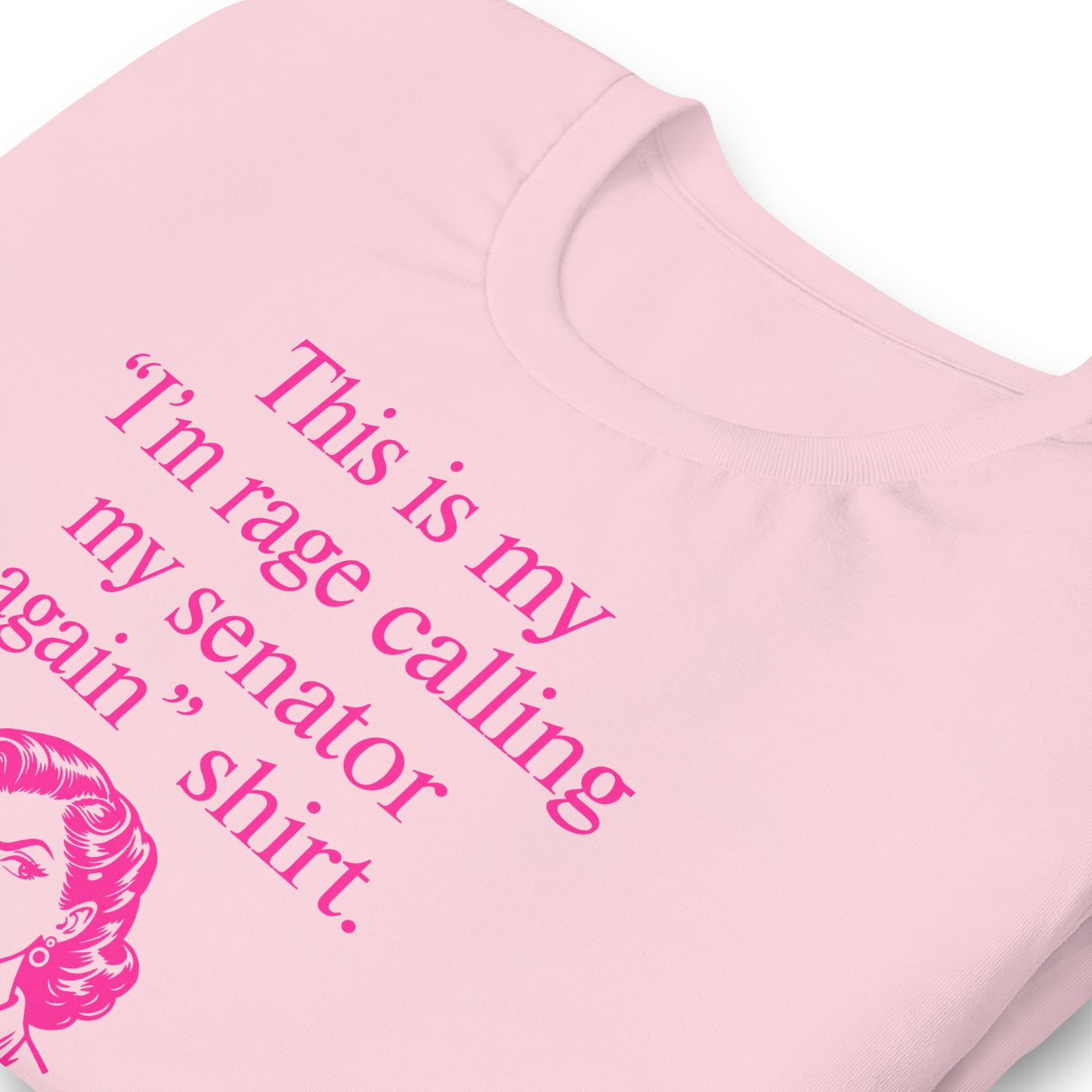 Close-up of t-shirt showing pink typography reading “This is my ‘I’m rage calling my senator again’ shirt.” with illustrated figure below.