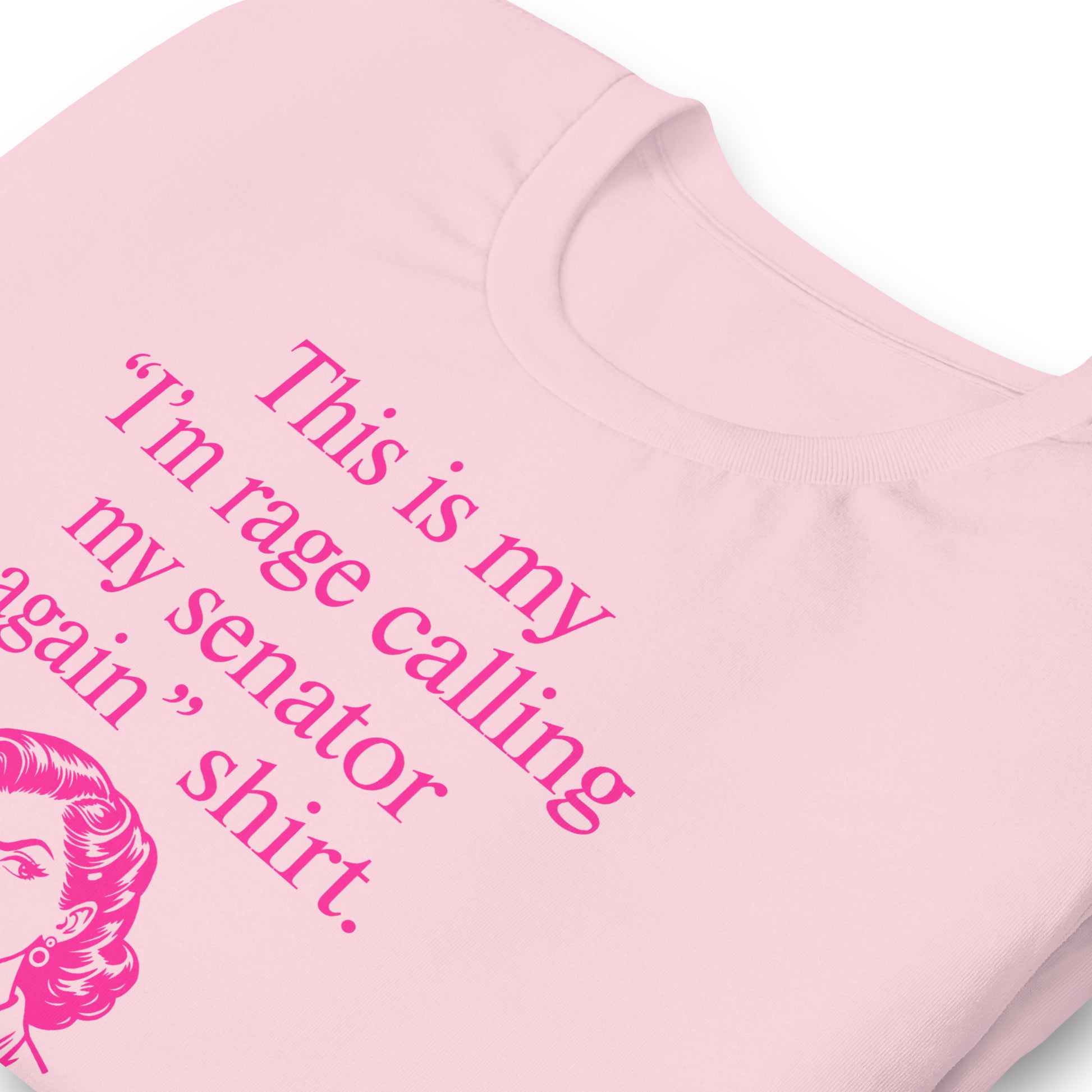 Close-up of t-shirt showing pink typography reading “This is my ‘I’m rage calling my senator again’ shirt.” with illustrated figure below.