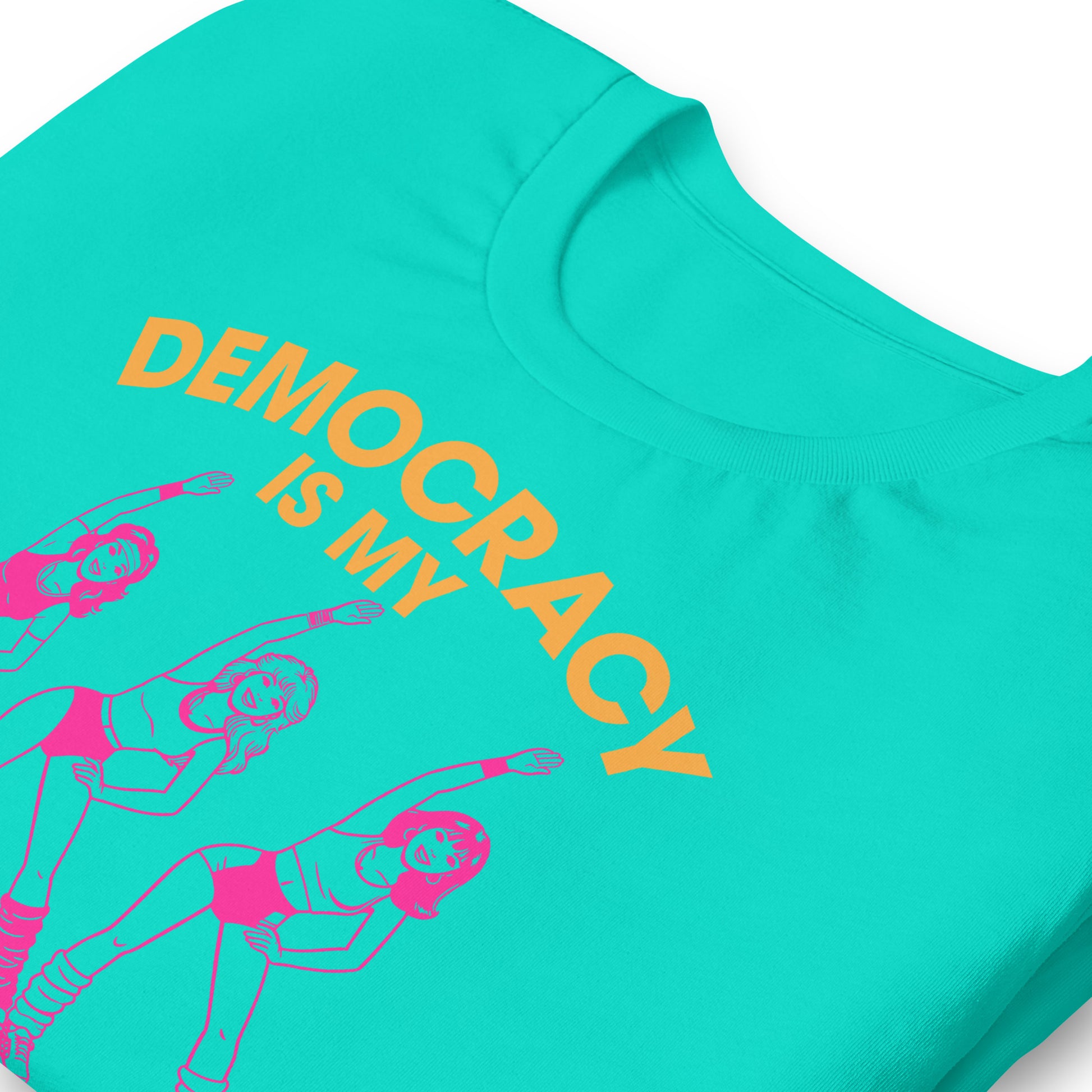 Close-up teal unisex T-shirt print showing retro aerobics dancers, curved democracy lettering, and cardio phrase in bold pink and orange typography.