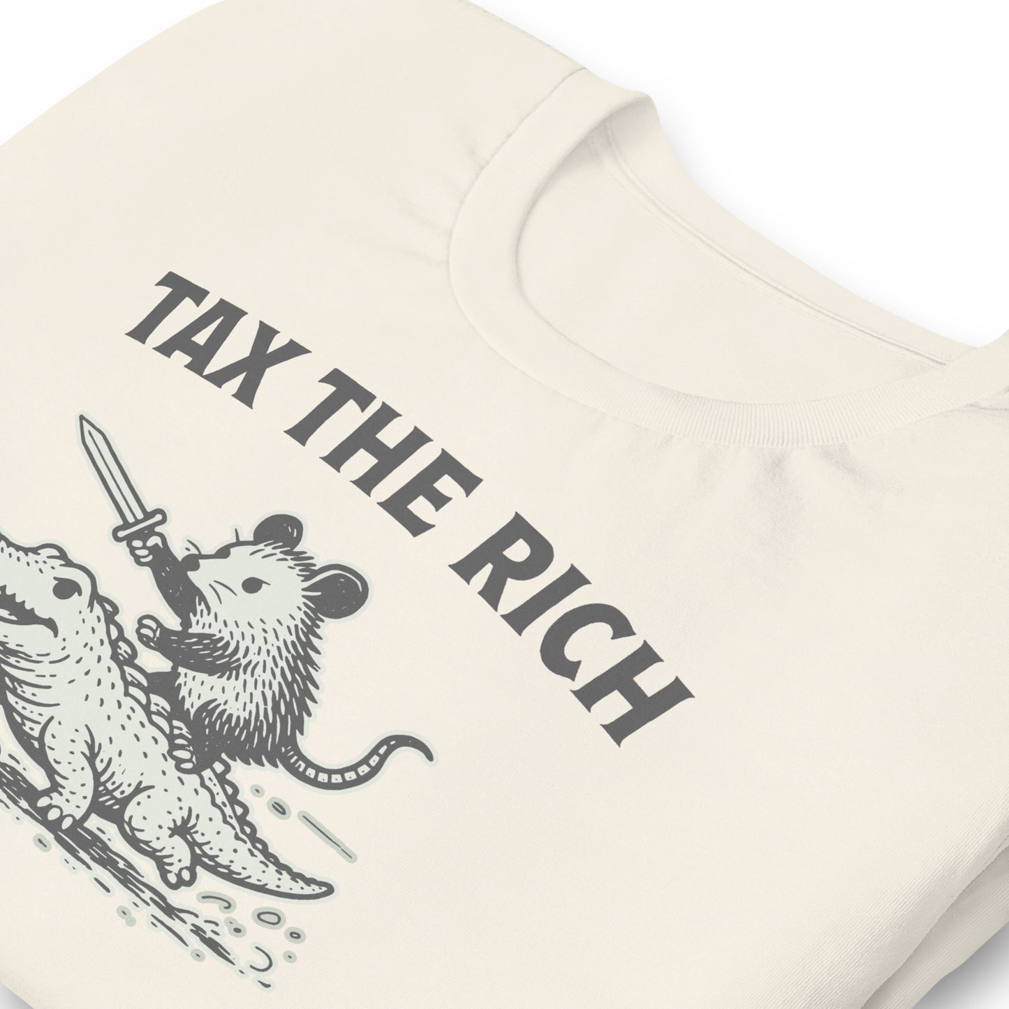 Close-up of vintage white t-shirt featuring a vintage woodcut-style opossum riding an alligator beneath the bold “Tax the Rich” message.