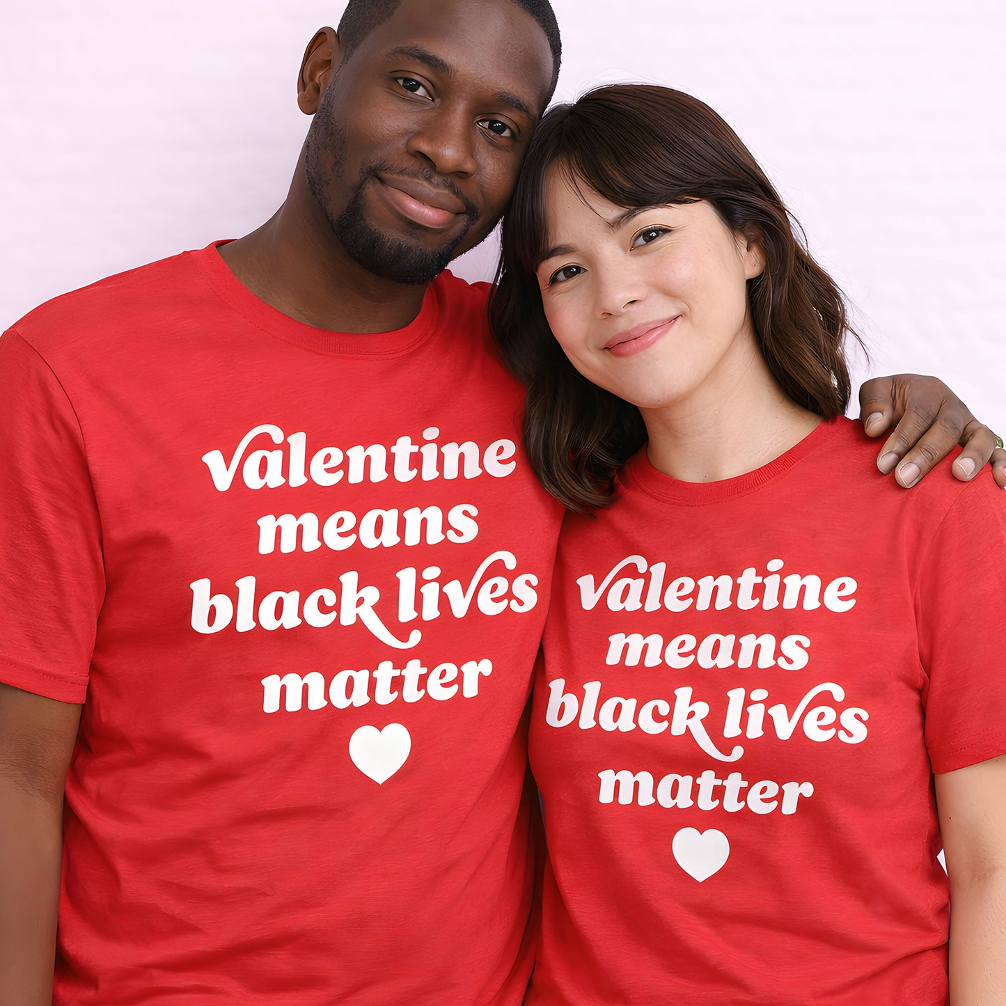 Two people wearing matching red unisex t-shirts featuring the phrase “Valentine means black lives matter,” heart graphic centered, photographed together against a neutral backdrop, progressive apparel.