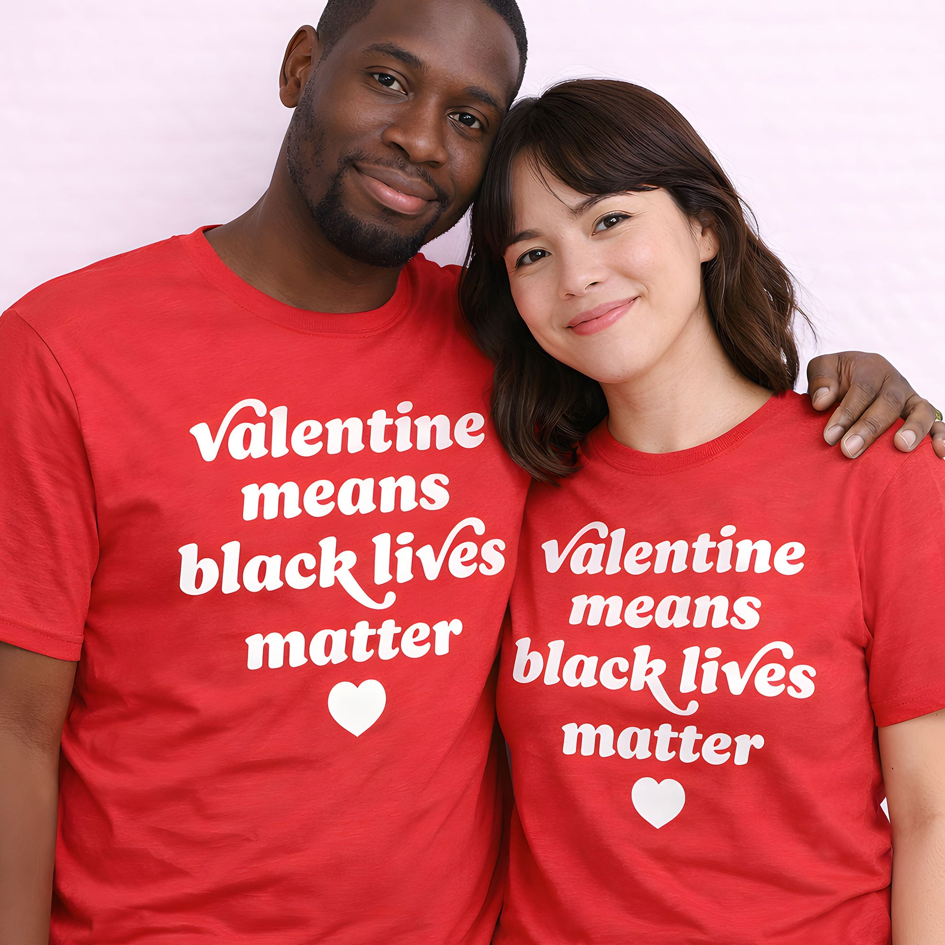 Two people wearing matching red unisex t-shirts featuring the phrase “Valentine means black lives matter,” heart graphic centered, photographed together against a neutral backdrop, progressive apparel.