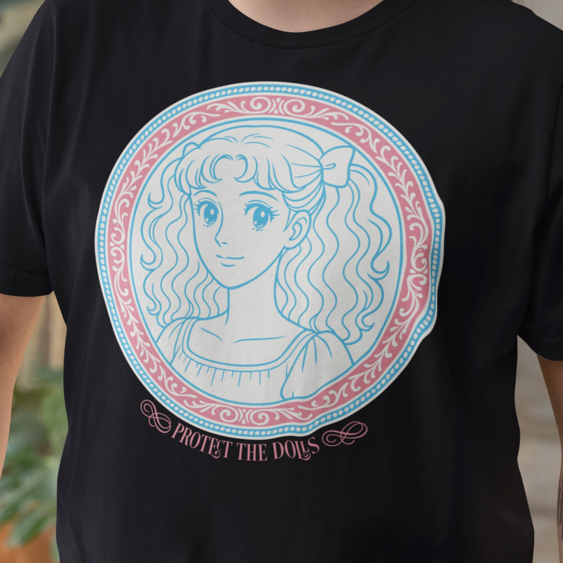 Close-up of the “Protect the Dolls” black t-shirt, with intricate pastel linework and ornate border details. Designed by Blue Wave USA to honor trans femme beauty and solidarity.