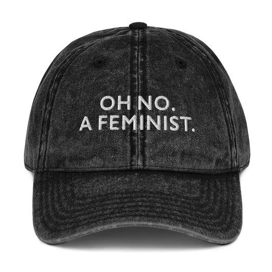 Black vintage embroidered cap featuring the phrase “OH NO. A FEMINIST.” in bold white lettering, a minimalist feminist design with a playful, unapologetic message.