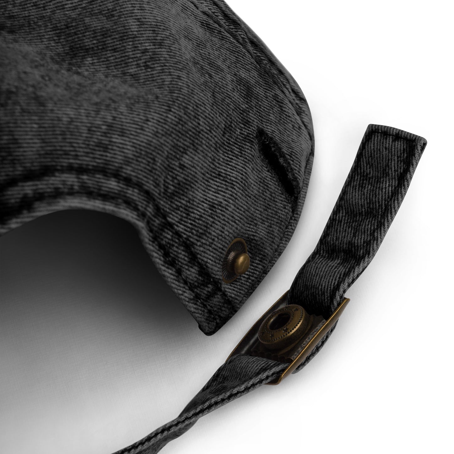 Close-up of the back strap on a black vintage cotton twill cap, showing adjustable metal buckle closure and distressed washed fabric texture.