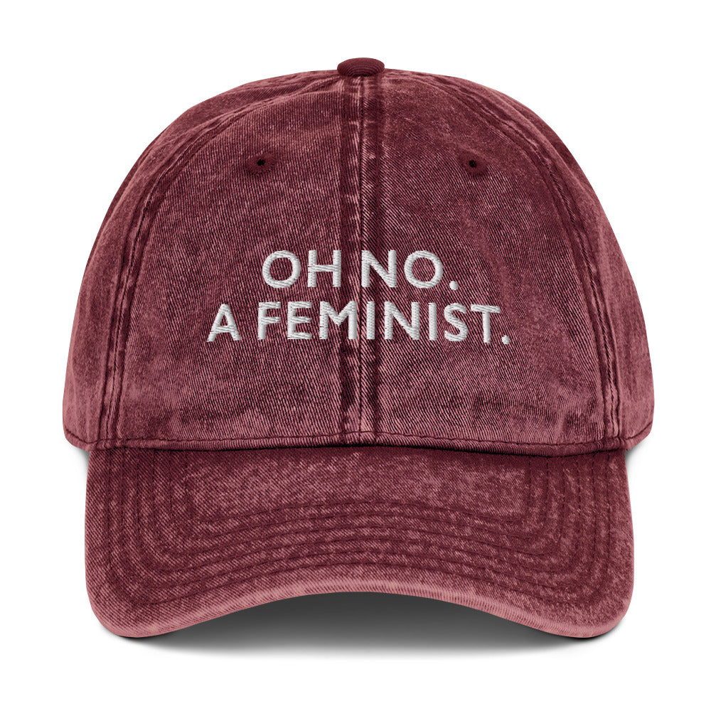 Burgundy vintage cap embroidered with “OH NO. A FEMINIST.” in clean white text, combining classic style with a bold feminist statement.