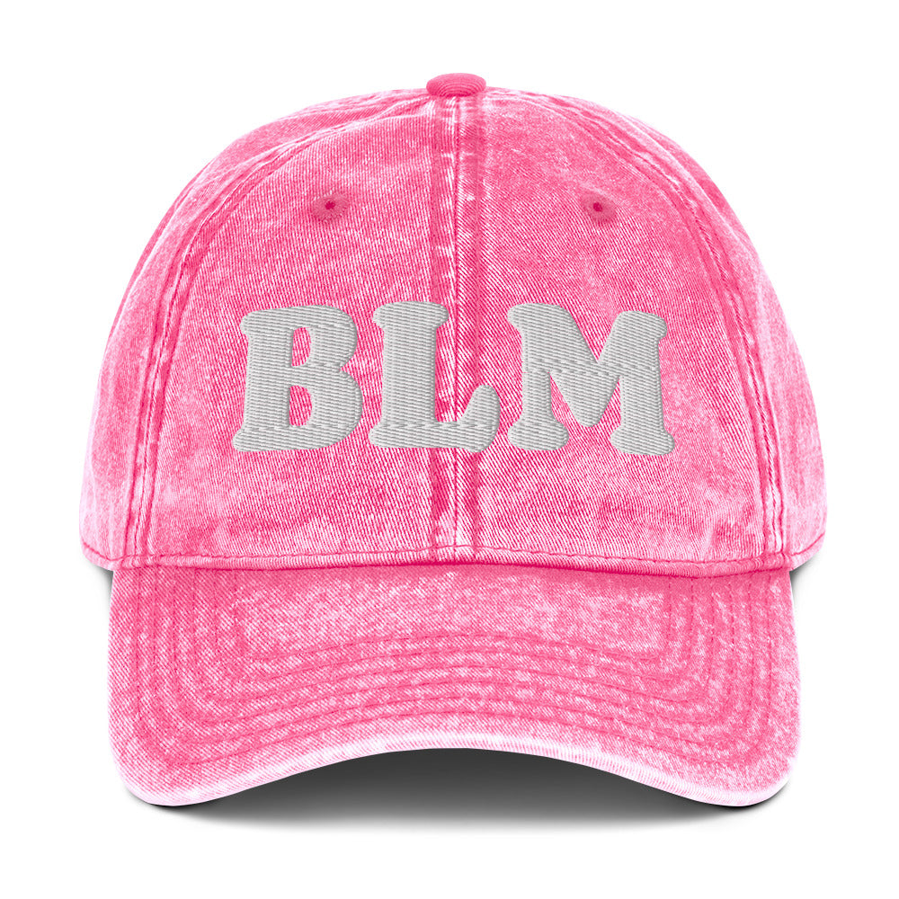 Pink vintage cotton twill cap with raised embroidered “BLM” lettering, washed cotton texture, curved brim, and soft unstructured crown.