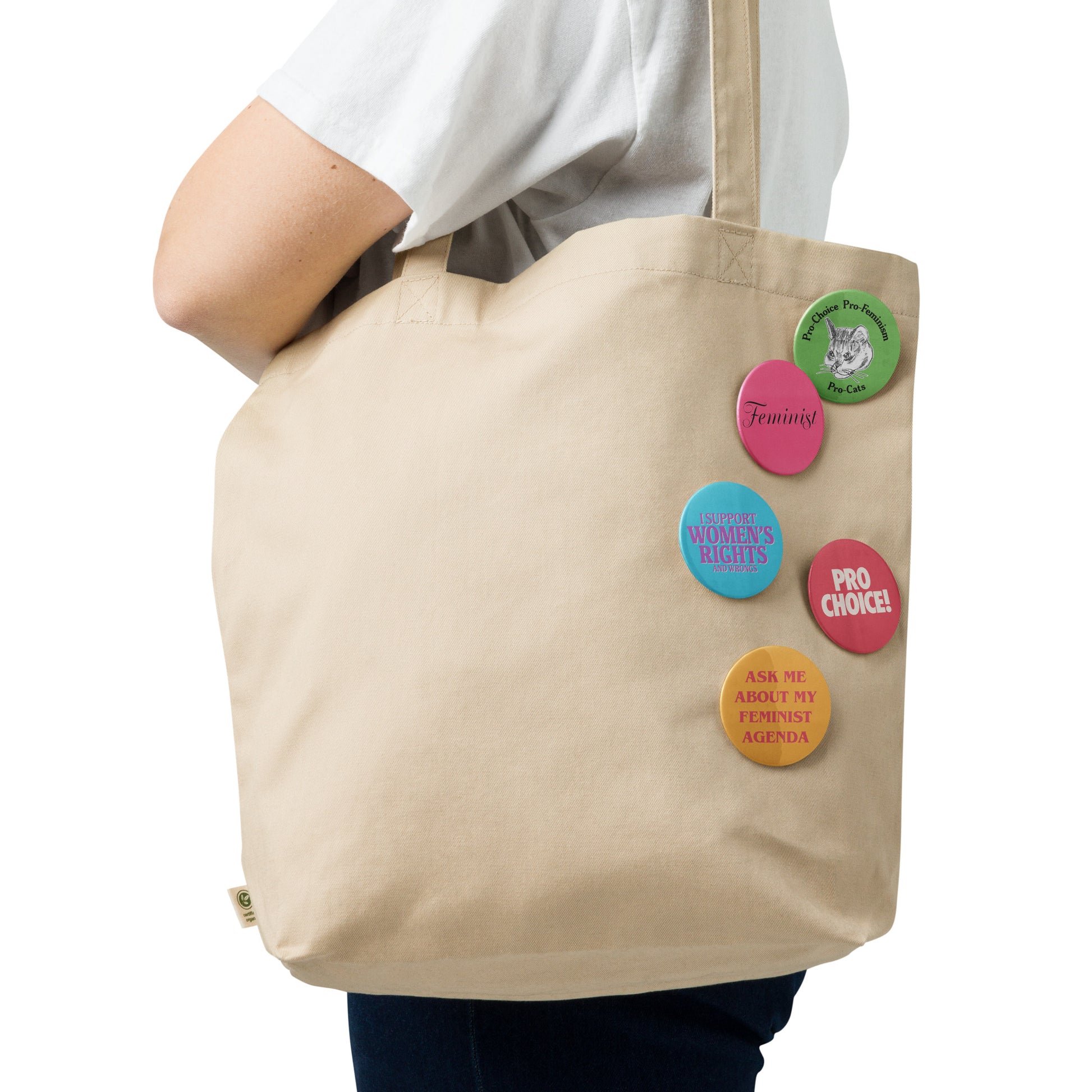 Canvas tote bag decorated with five colorful feminist pin buttons featuring pro-choice slogans, feminist typography, and retro activist-inspired button designs.