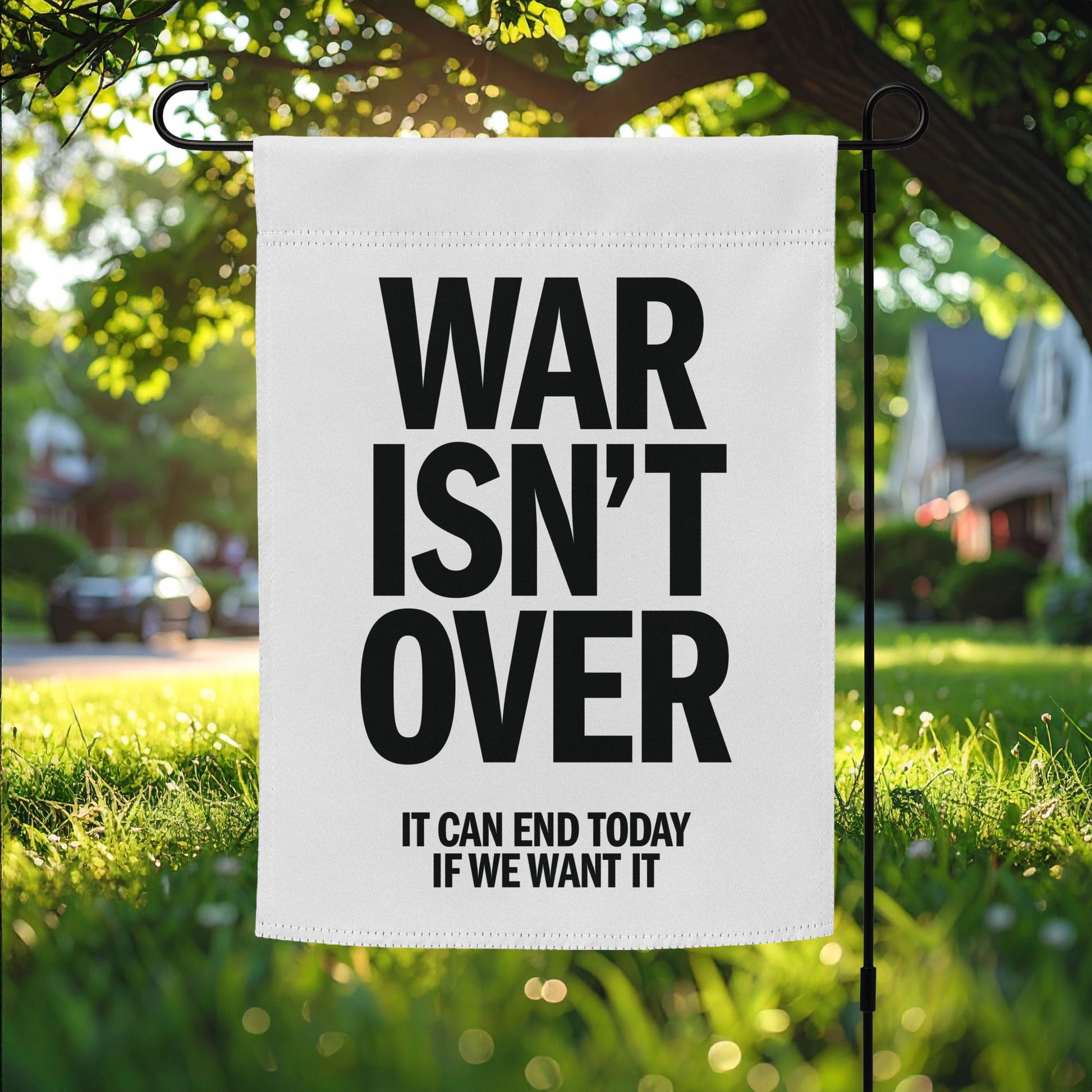 Garden flag featuring bold black “WAR ISN’T OVER” text with “IT CAN END TODAY IF WE WANT IT” below, minimalist anti-war protest outdoor decor.