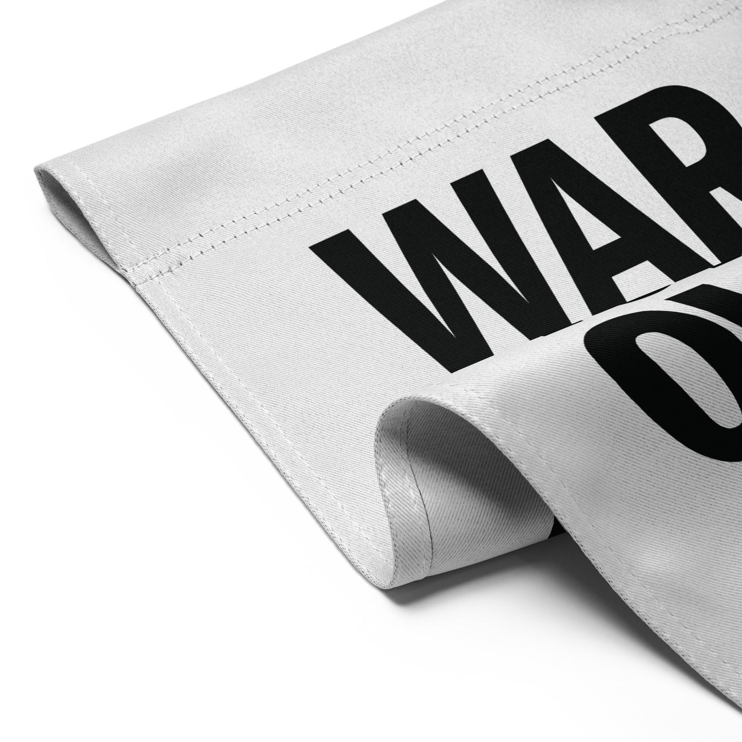 Folded white garden flag detail highlighting crisp black “WAR” typography from the minimalist anti-war outdoor message design.
