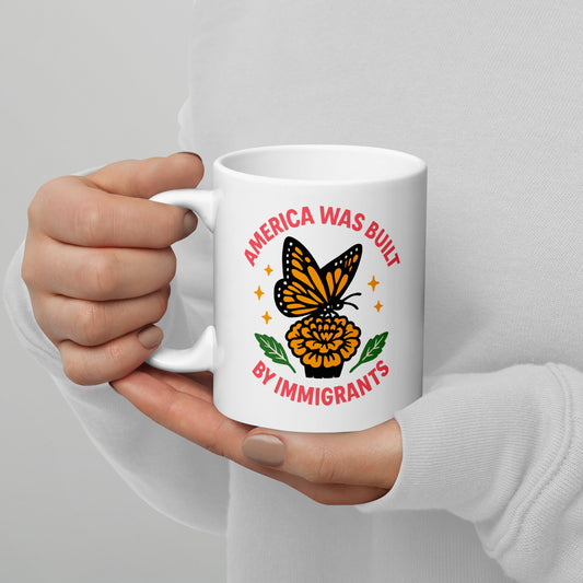 White ceramic mug with “America Was Built by Immigrants” monarch butterfly design, activist coffee mug celebrating diversity and inclusion.