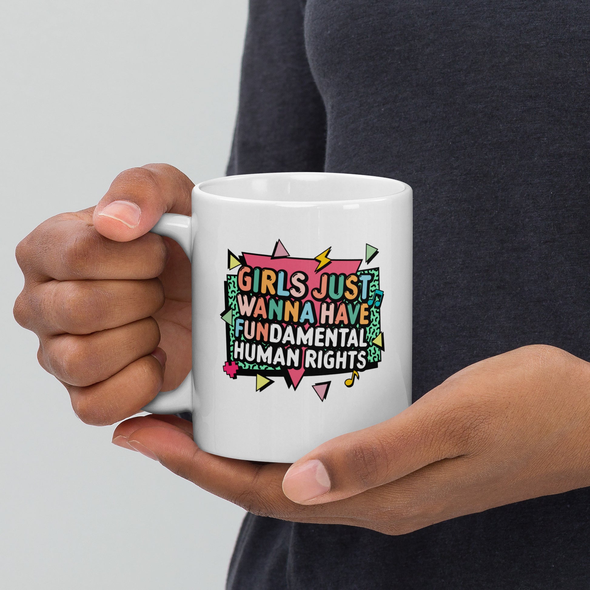 White ceramic mug with the colorful retro slogan “Girls Just Wanna Have Fundamental Human Rights” in bold pink, yellow, and mint typography with lightning bolt accents. Feminist coffee mug by Blue Wave USA.