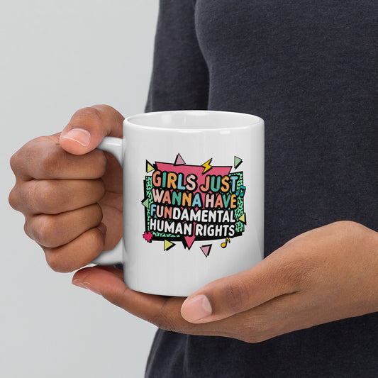 White ceramic mug with the colorful retro slogan “Girls Just Wanna Have Fundamental Human Rights” in bold pink, yellow, and mint typography with lightning bolt accents. Feminist coffee mug by Blue Wave USA.